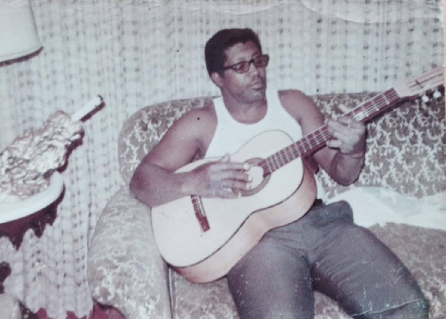 Bob Diddley Playing Guitar On Couch Wallpaper