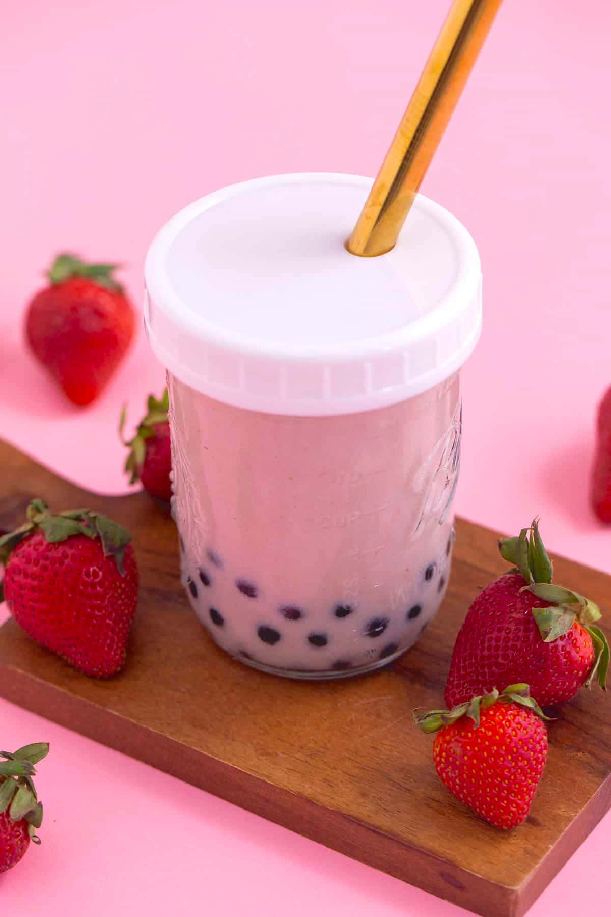A Cup Of Bubble Tea With Strawberries And A Gold Spoon
