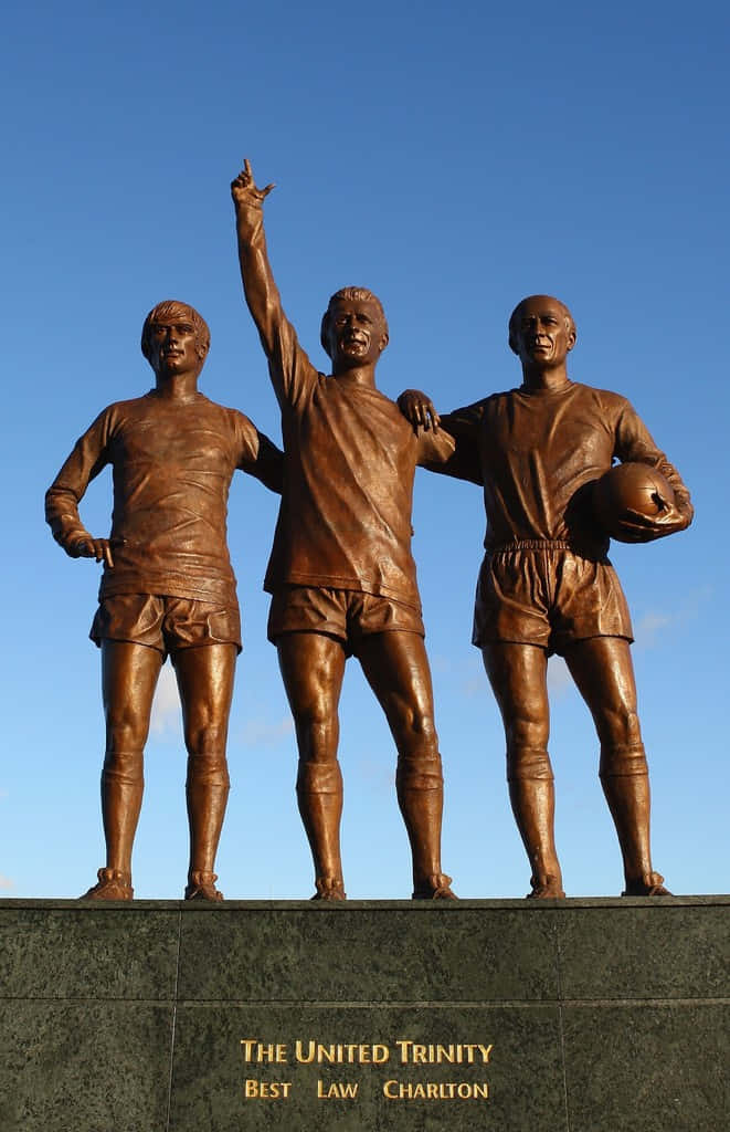 Leggendariobobby Charlton - Statua Della Trinità Del Manchester United Sfondo