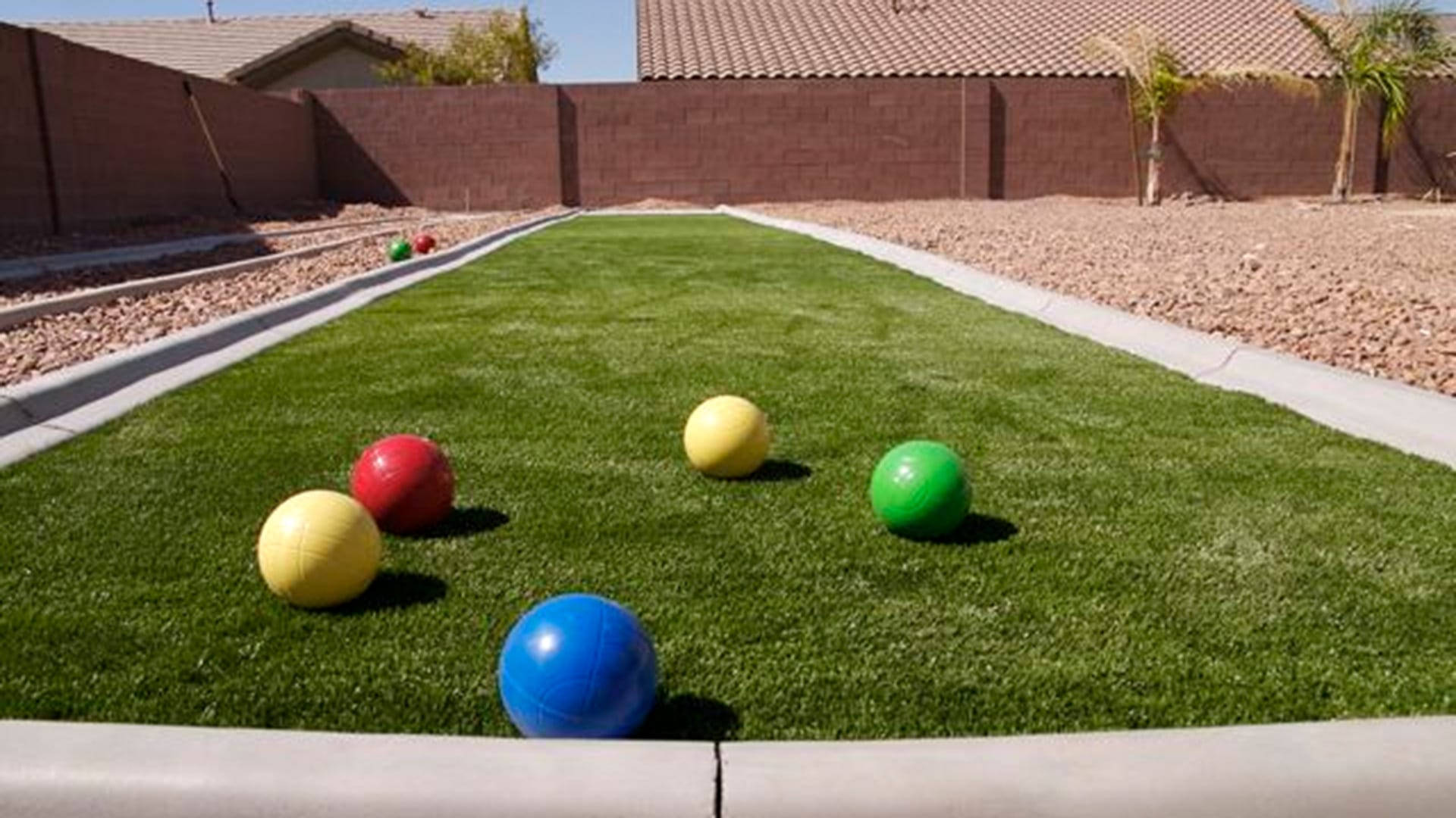 A Competitive Bocce Ball Game on a Vibrant Green Court Wallpaper