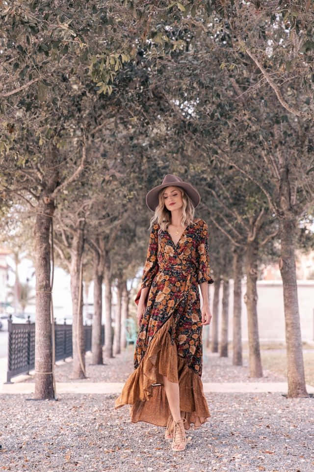 A Woman In A Floral Dress Walking Through A Park