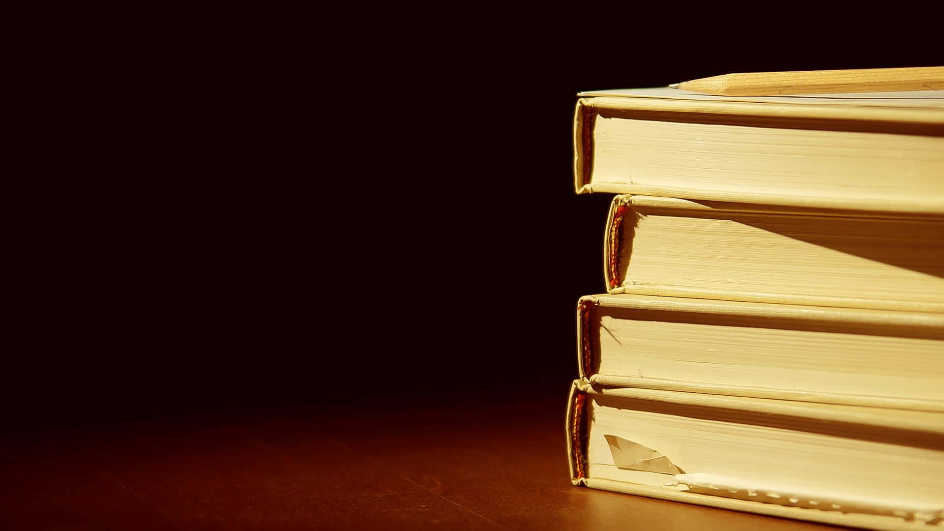 A Stack Of Books On A Table With A Light Behind Them