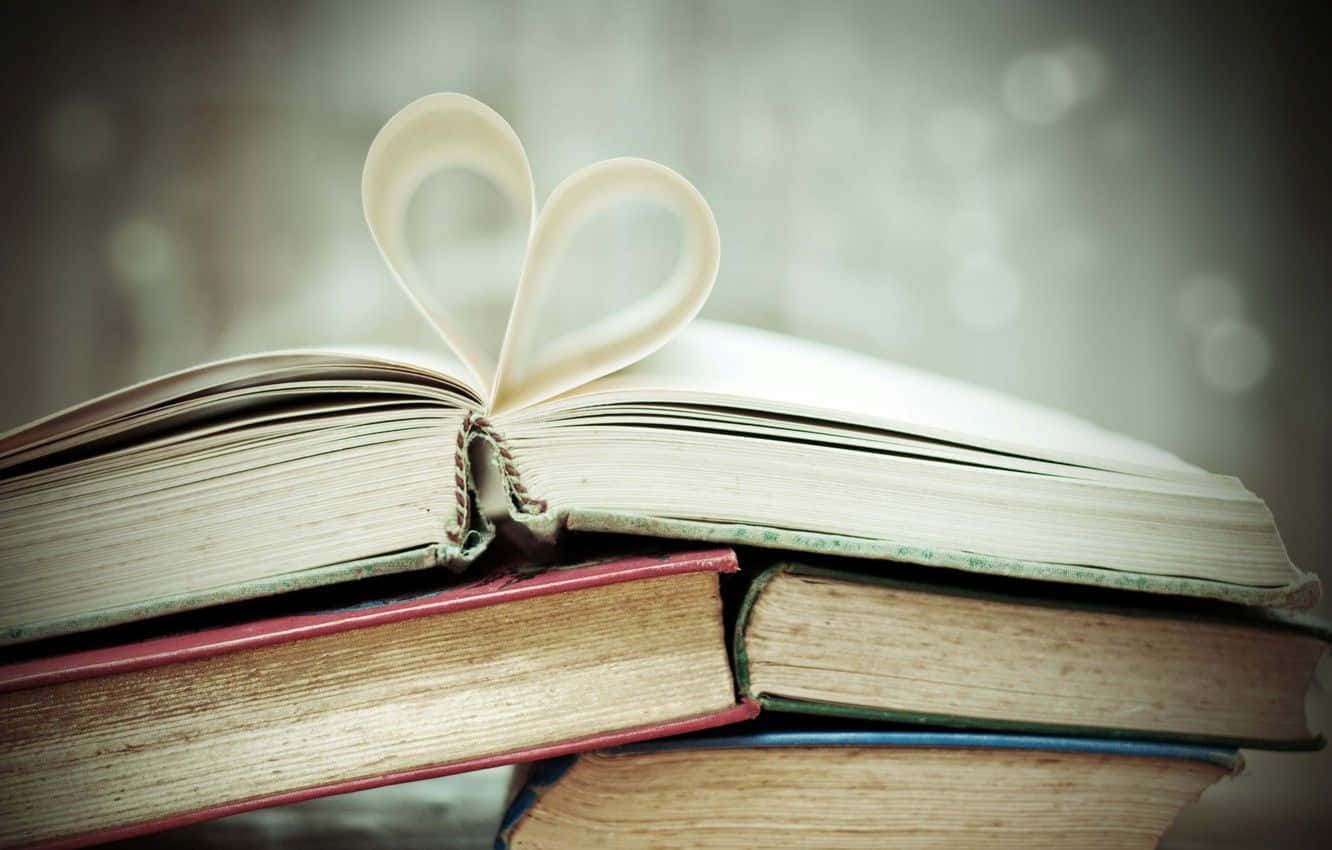 A Stack Of Books With A Heart Shaped Paper On Top