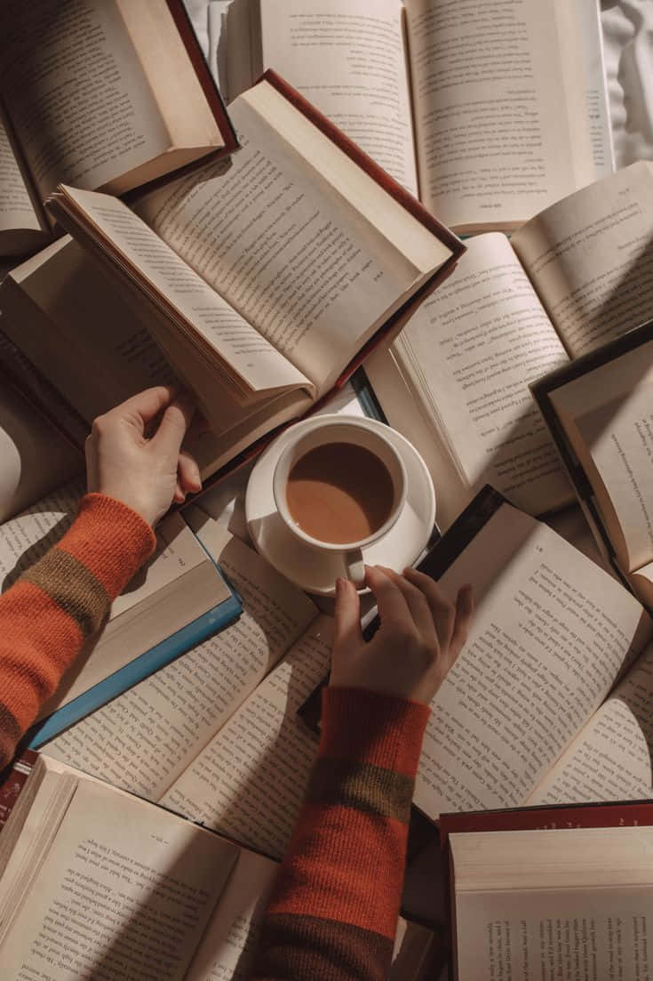 A Person Reading A Book With A Cup Of Coffee