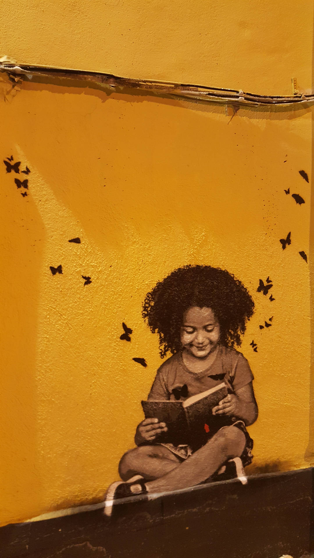 Graffiti wallpaper of little girl reading a book.