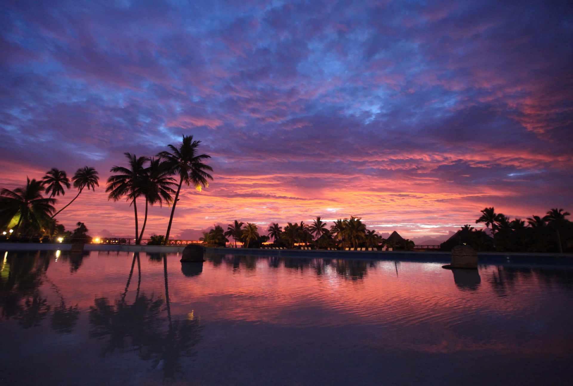En solnedgang over et swimmingpool med palmetræer