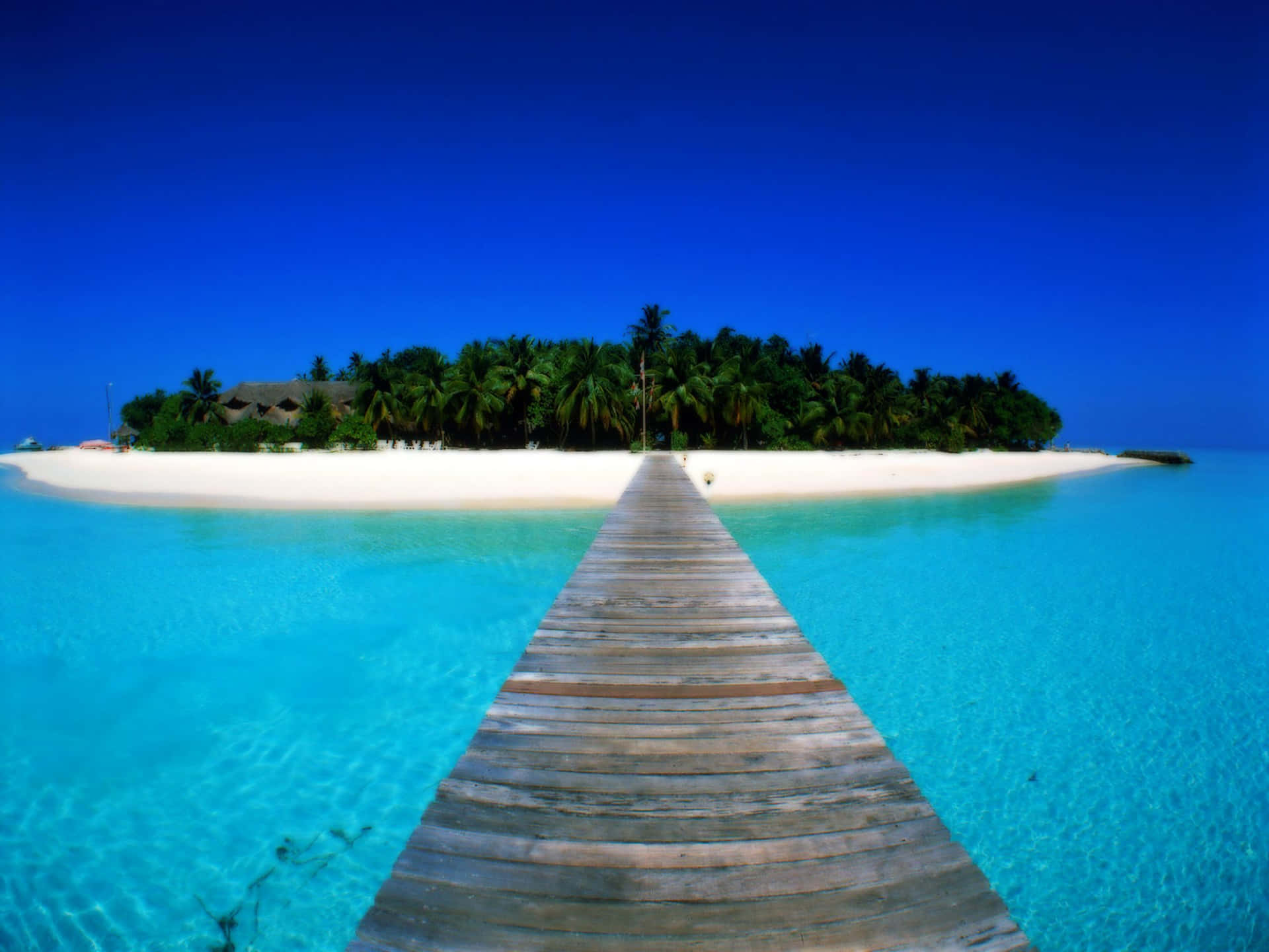 A Wooden Walkway Leading To An Island In The Middle Of The Ocean