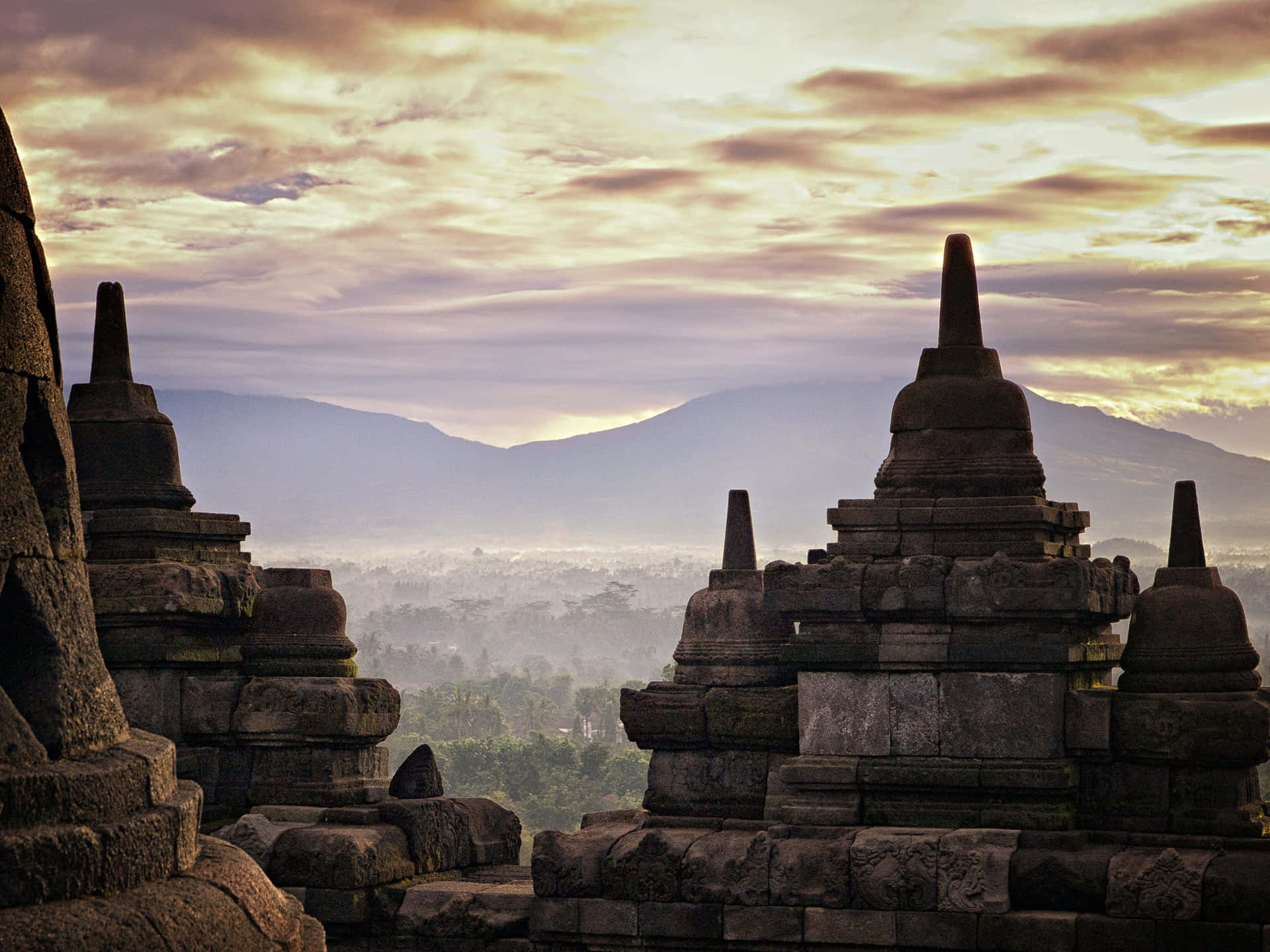 Breathtaking view of Borobudur Temple under a bright yellow sky. Wallpaper