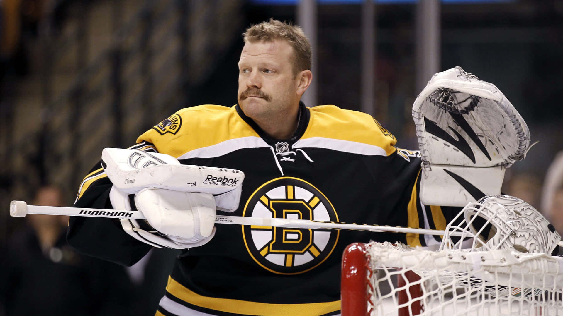 Unportero De Los Boston Bruins Está Sosteniendo Su Máscara De Portero.