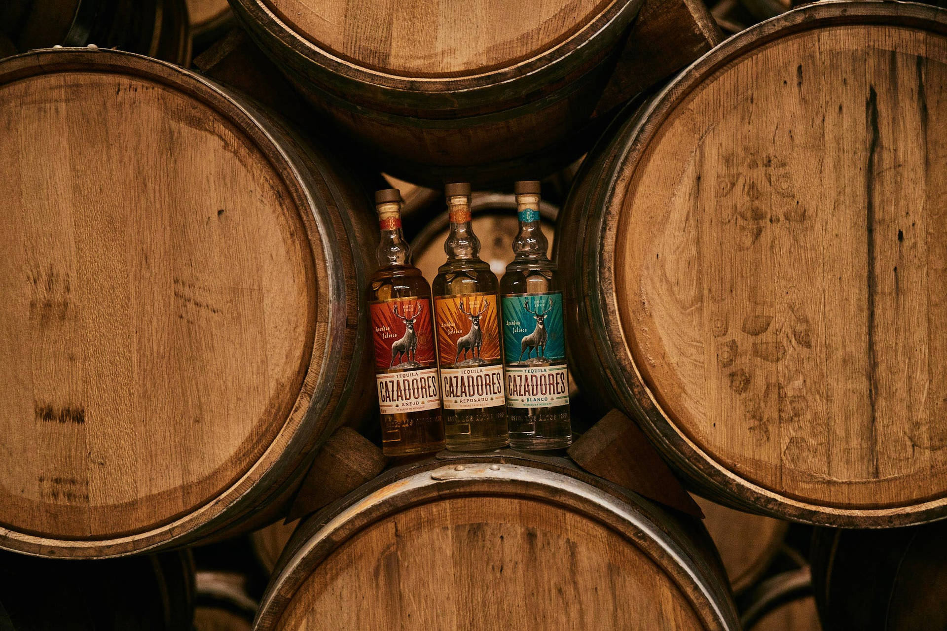 Exquisite Bottles of Cazadores Tequila Nestled between Authentic Aging Barrels. Wallpaper