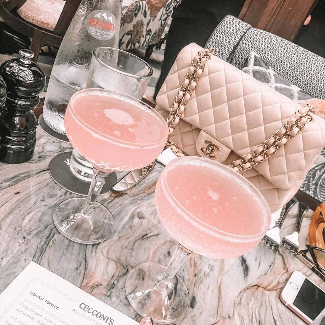 En bord med to pink drikke og en taske. Wallpaper