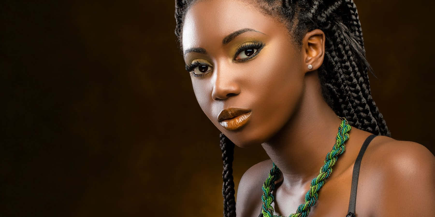 En smuk sort kvinde med fletninger og grøn halskæde