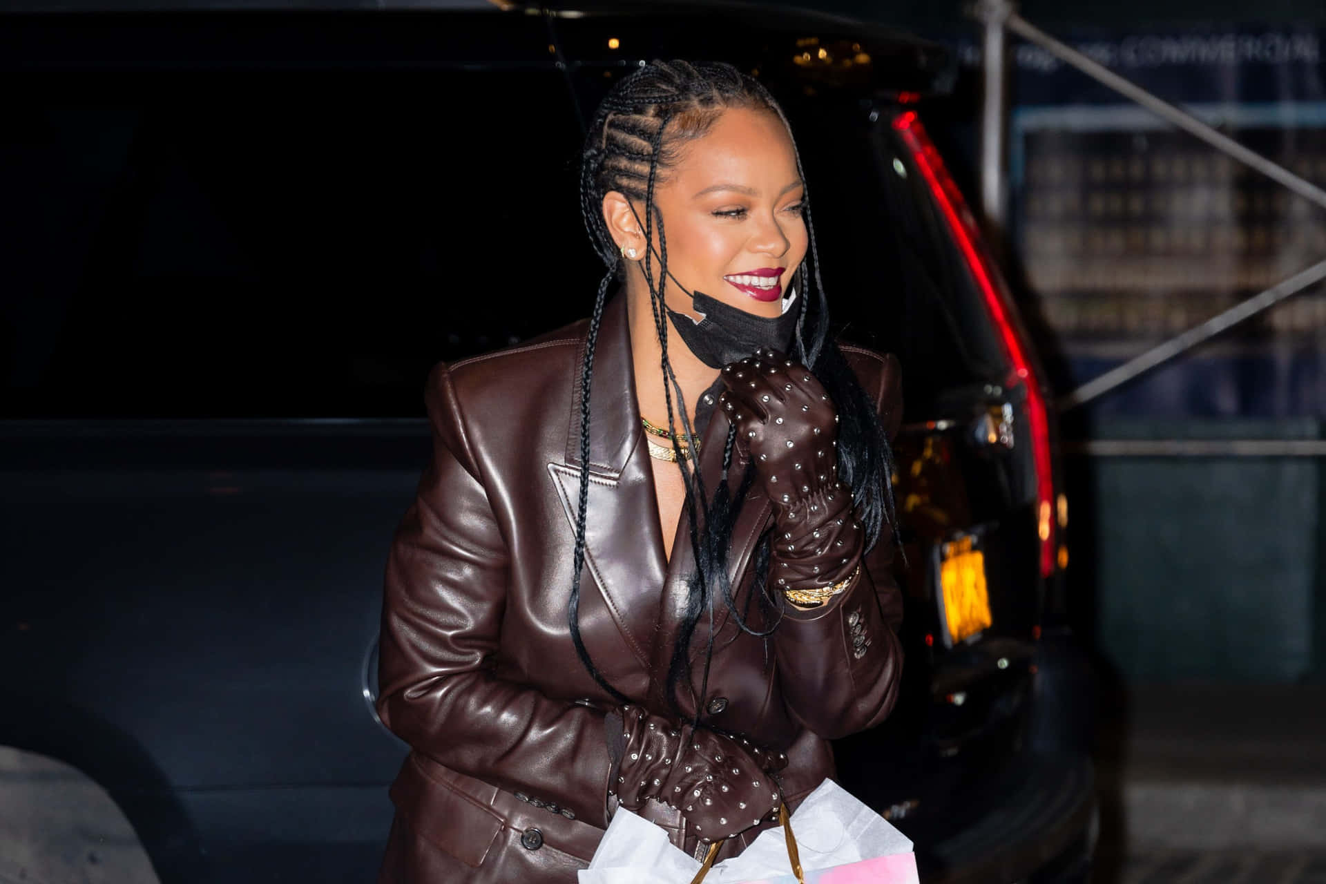 Rihanna iført en brun læderjakke og lyserød taske