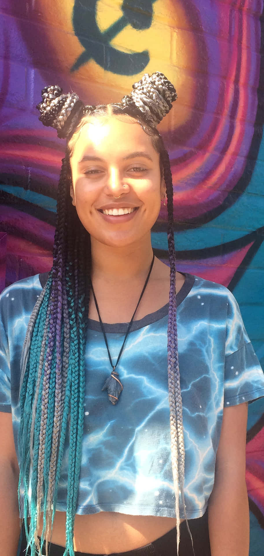 A Young Woman With Braids In Front Of A Graffiti Wall