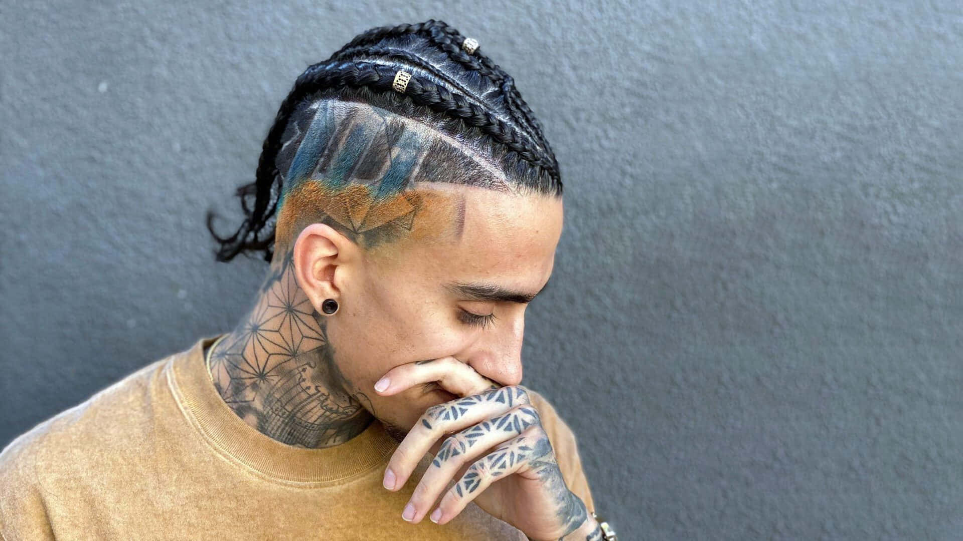 A Man With Tattoos And A Braided Hairstyle