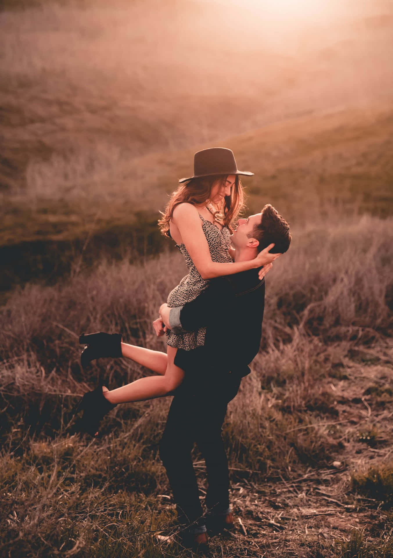 A Couple Is Carrying Each Other In The Field At Sunset