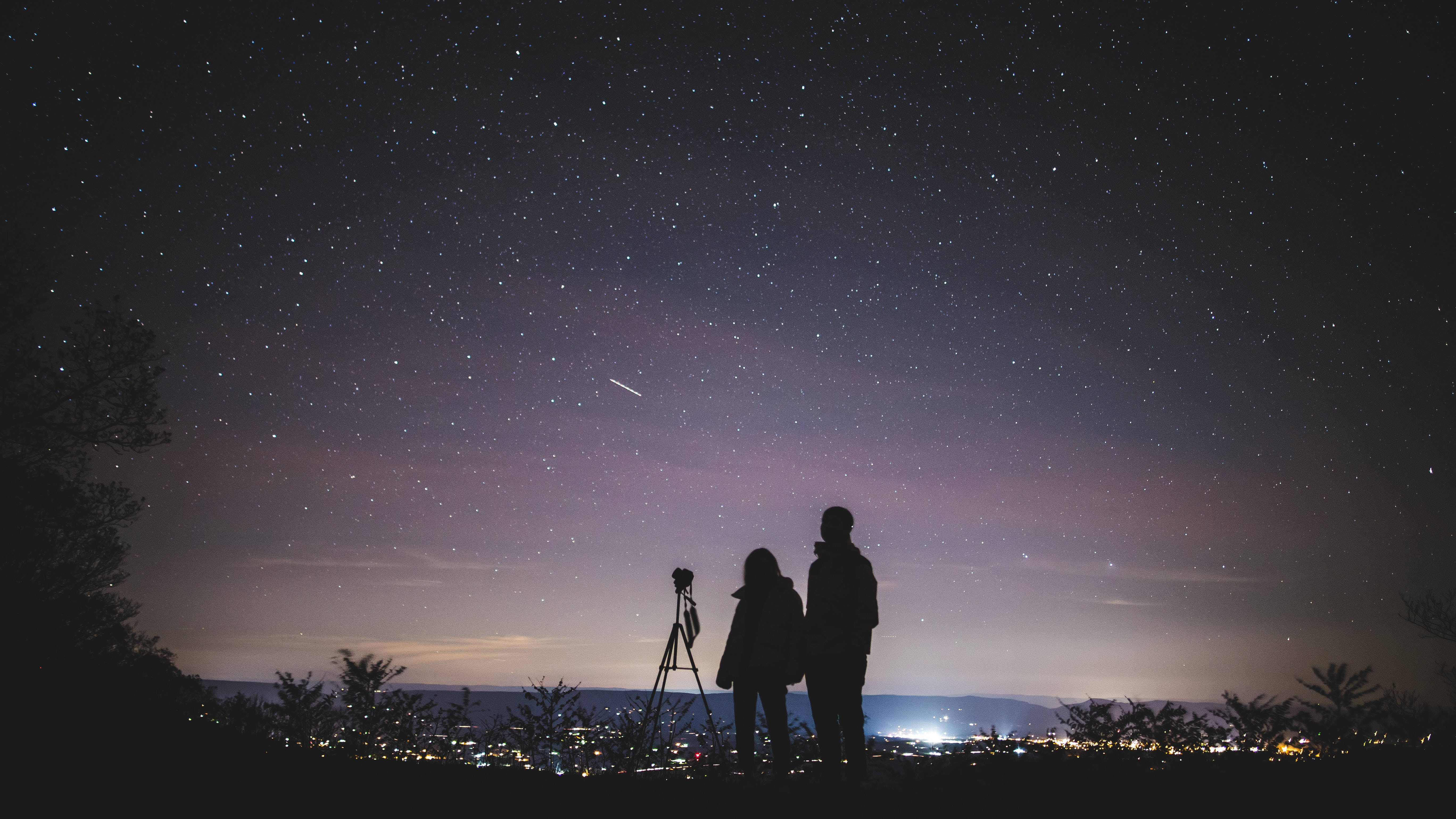 Kæreste og kæreste kigger på stjernerne om natten. Wallpaper