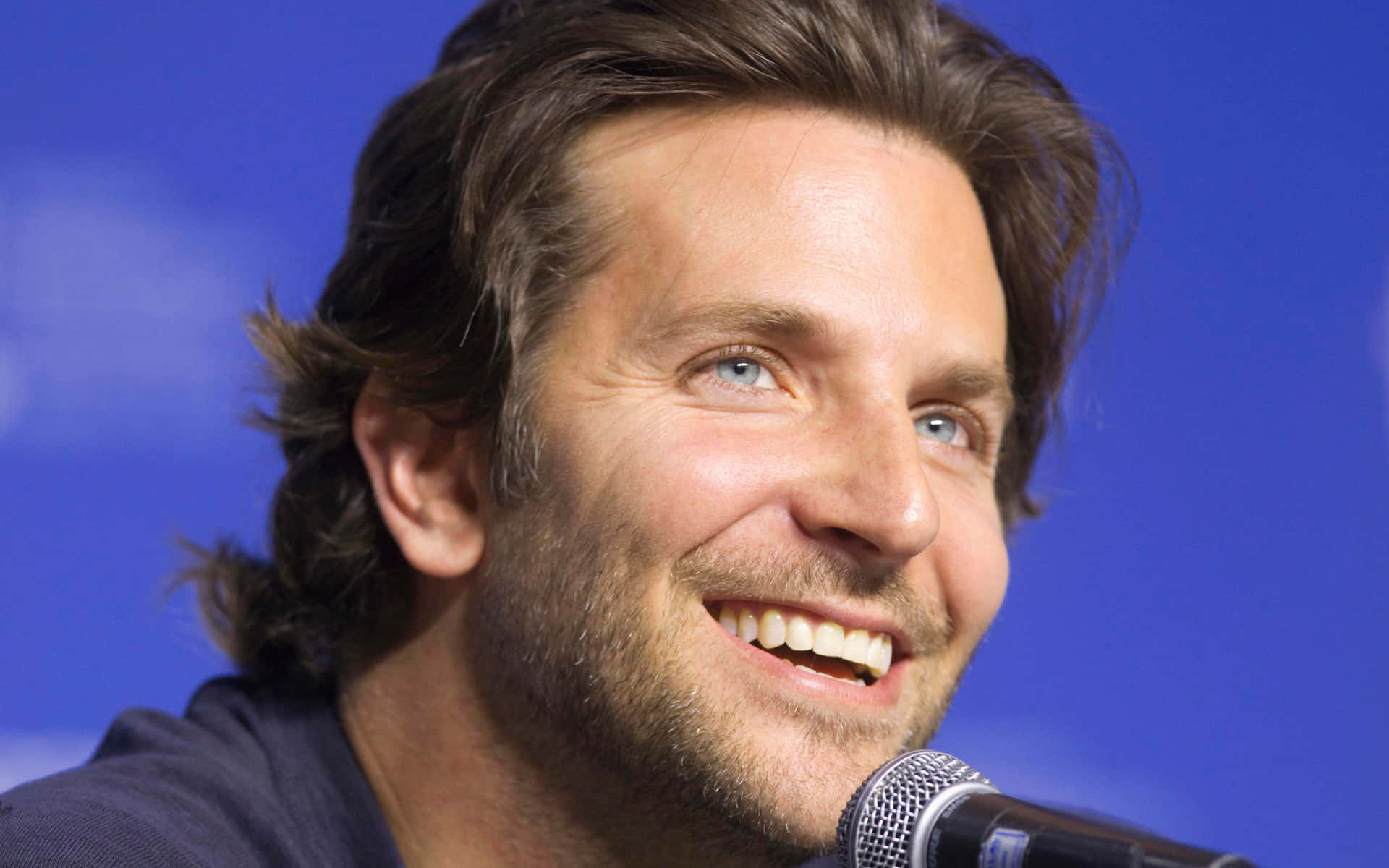 Bradley Cooper - A Man Smiling Into A Microphone