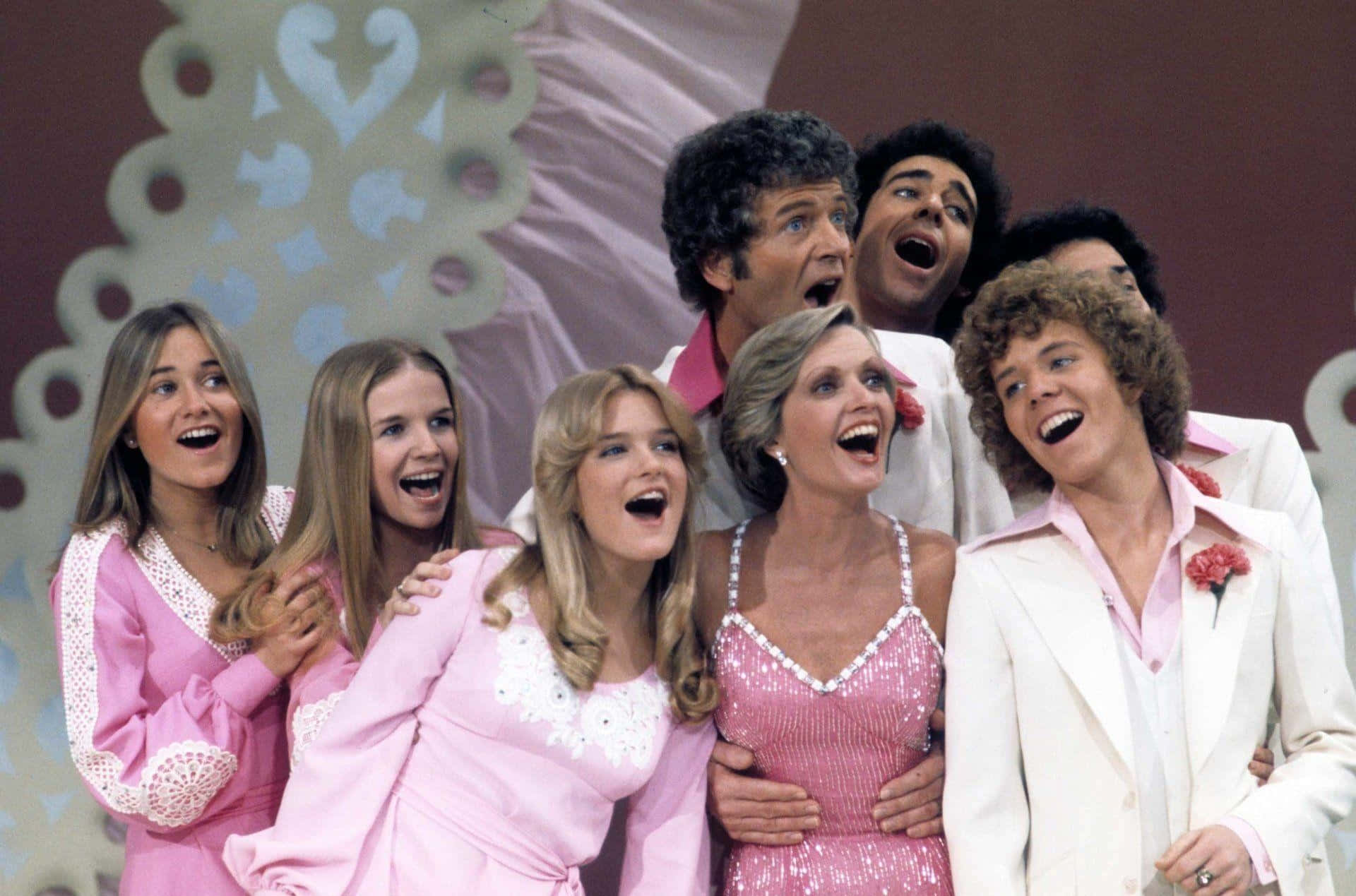 A Group Of People In Pink Suits Are Smiling