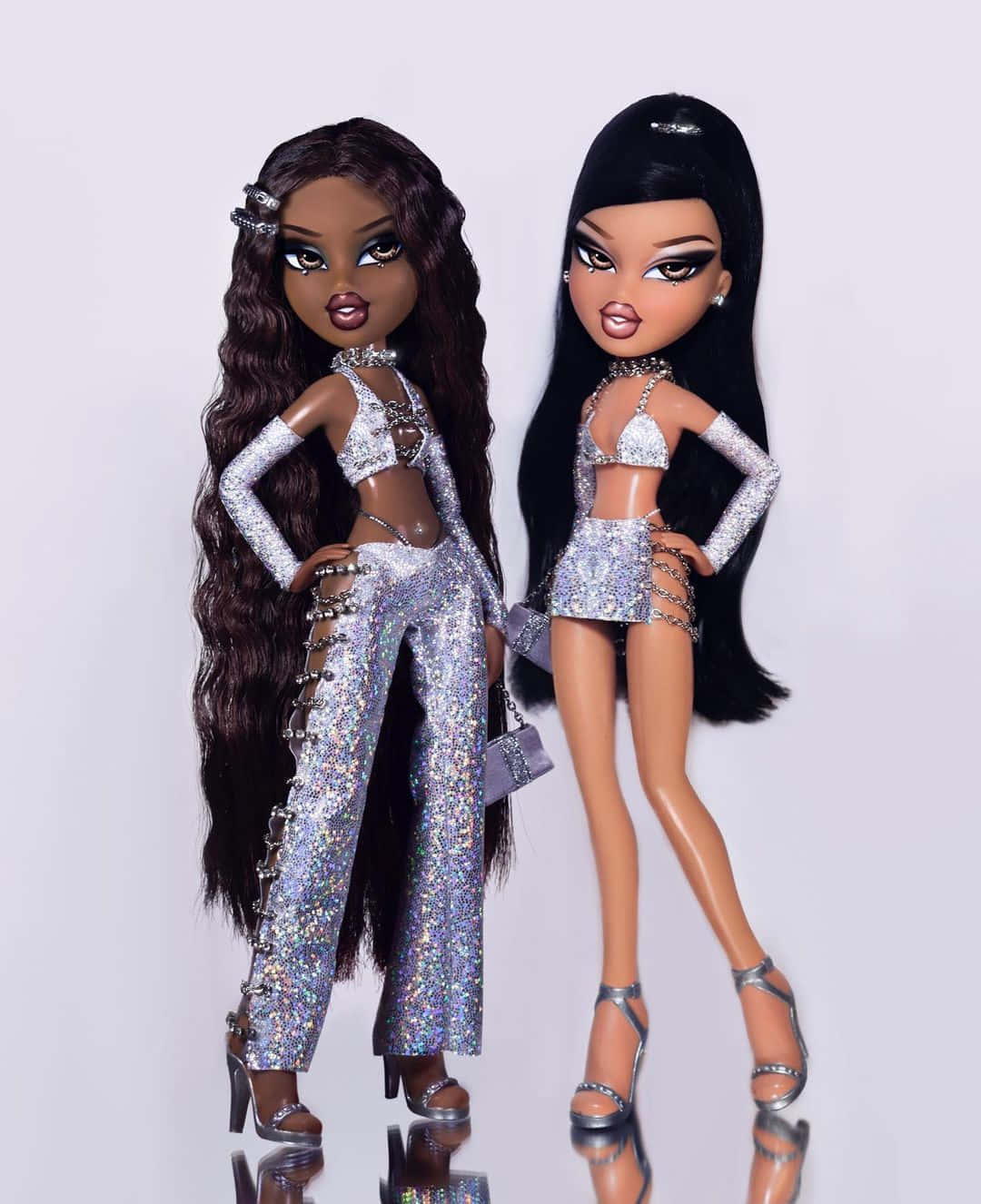 Two Dolls In Silver Outfits Standing Next To Each Other