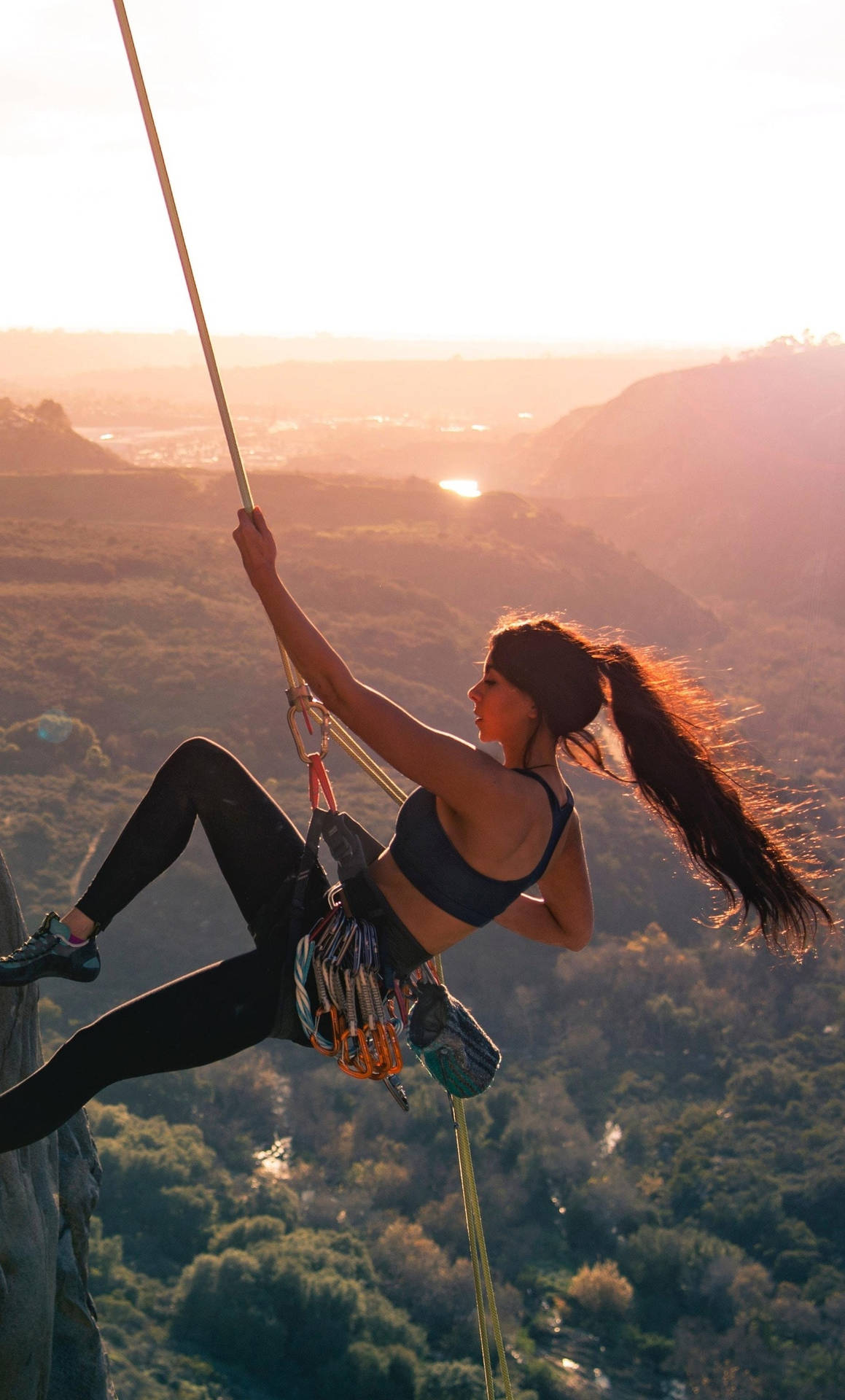 Caption:  Fearless Female Rock Climber Ascending a Cliff Wallpaper
