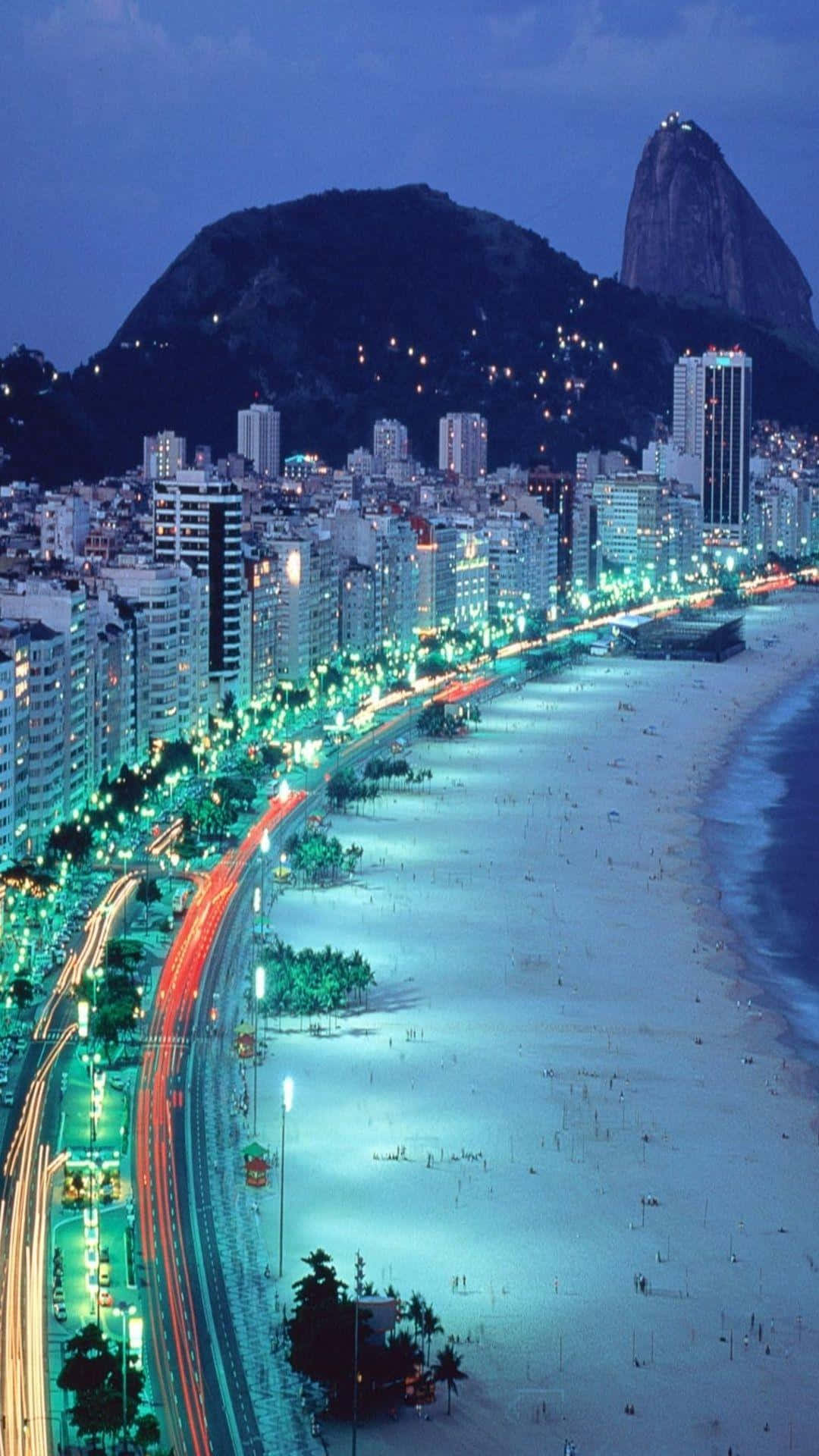 A City At Night With A Beach And Mountains