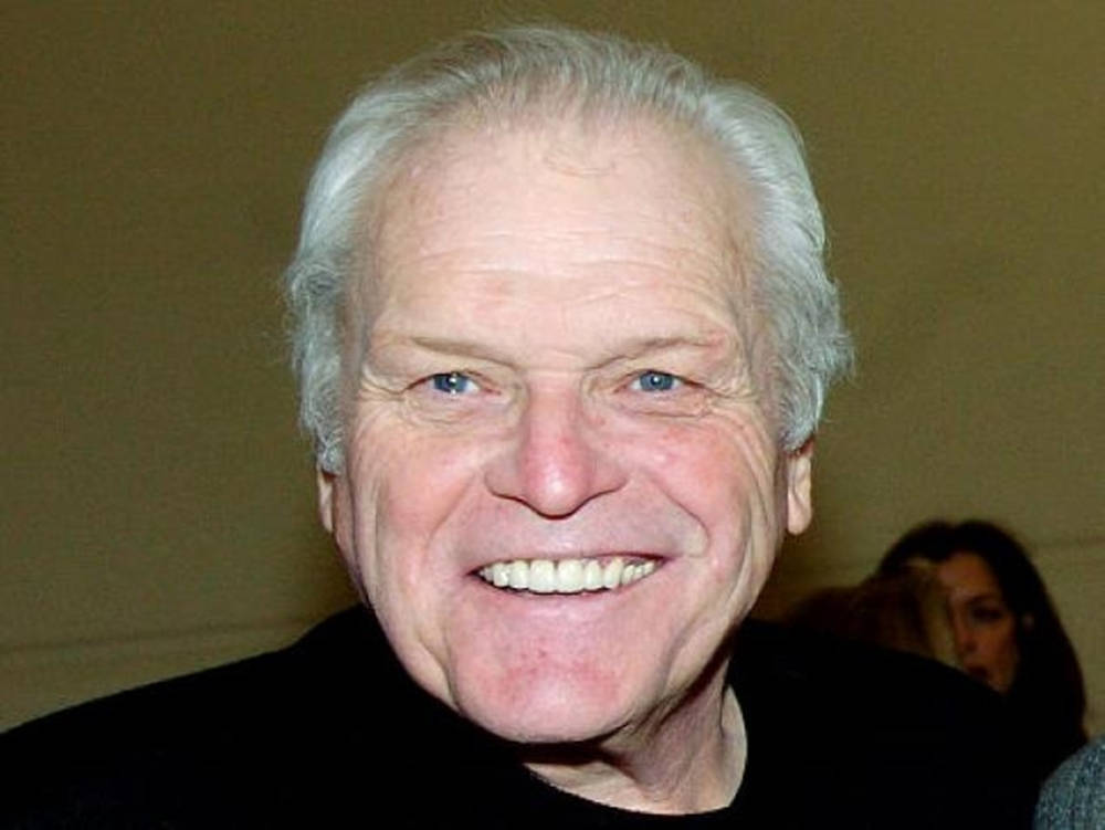 Brian Dennehy Smiling On Brown Background Wallpaper