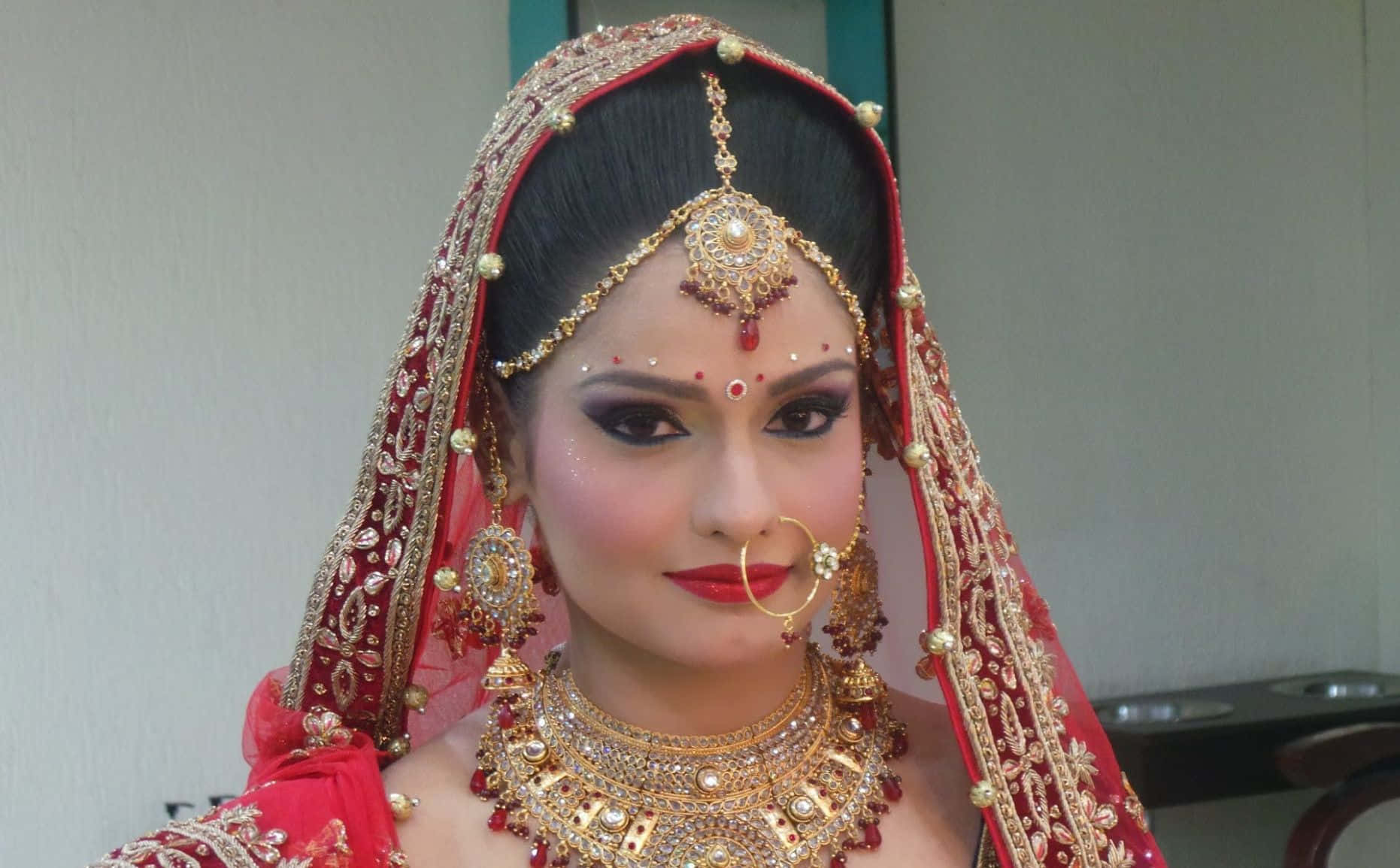 A Woman In Red And Gold Bridal Makeup