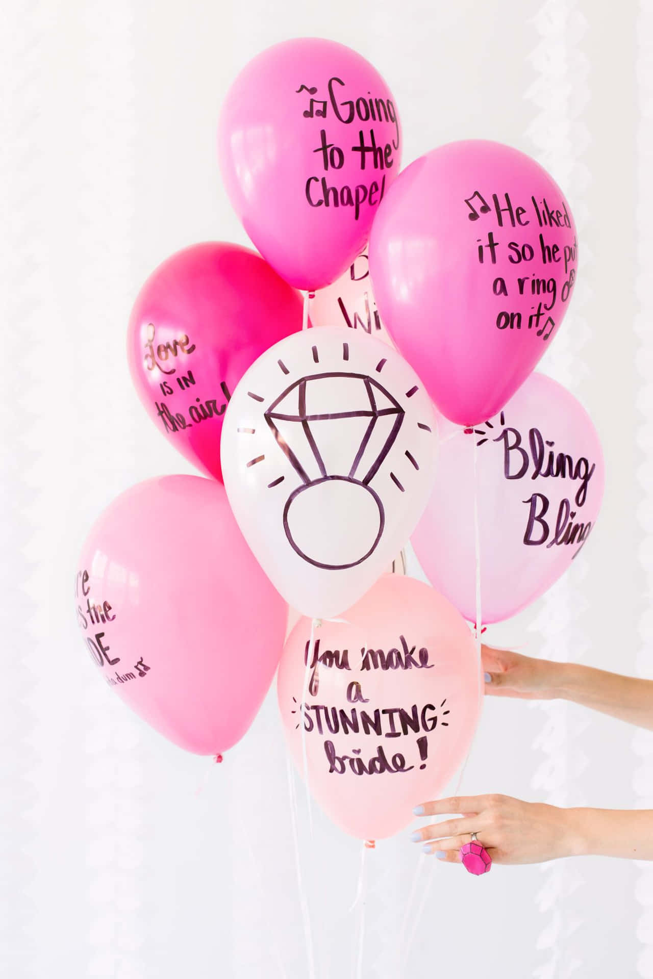 A Person Holding Pink Balloons With Writing On Them