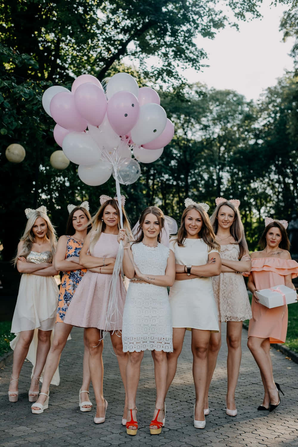 A Group Of Women In White Dresses Holding Balloons