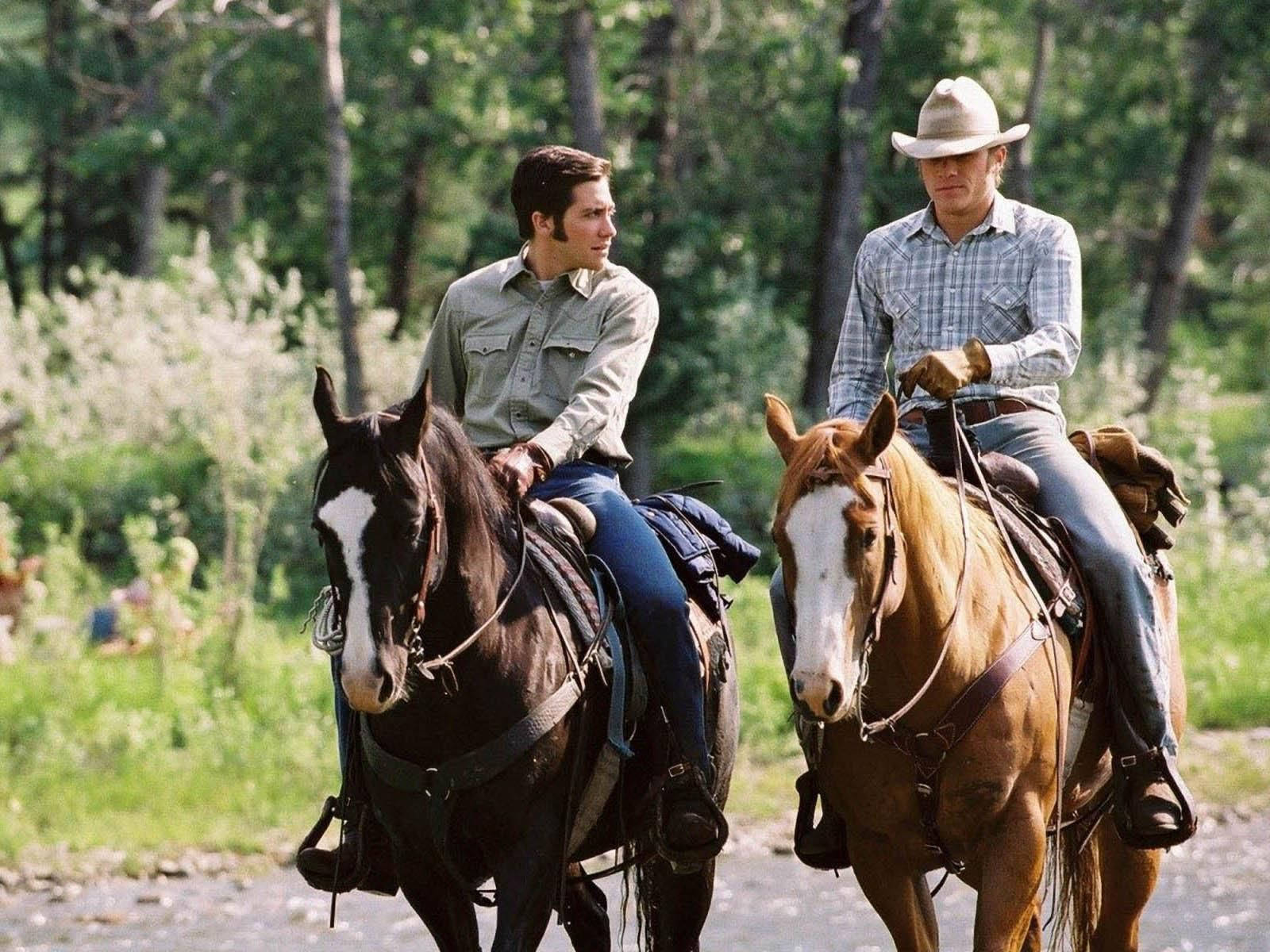 Tag et billede af det farverige landskab fra filmen 'Brokeback Mountain' mens heste ridende i forgrunden. Wallpaper