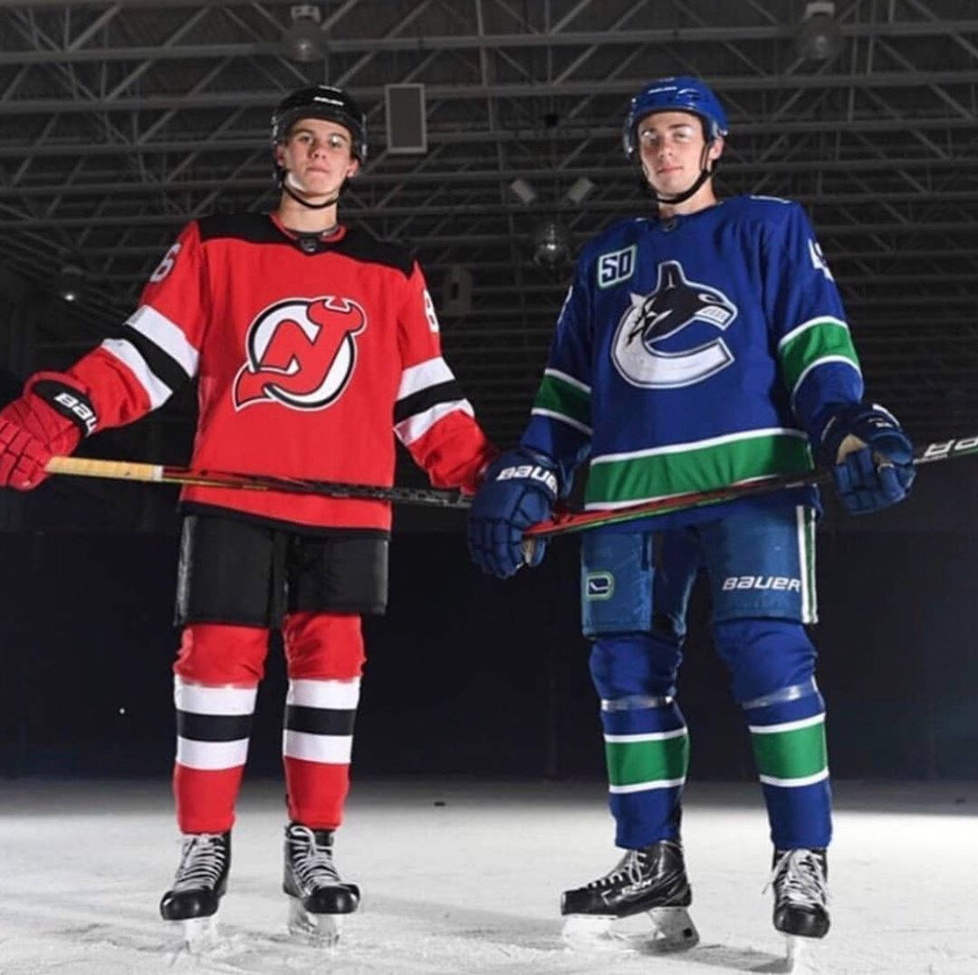 NHL Stars Quinn Hughes and Jack Hughes Posing on Ice Rink Wallpaper