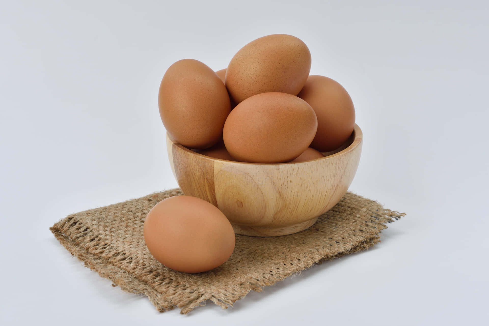 A collection of fresh brown eggs on a rustic table Wallpaper