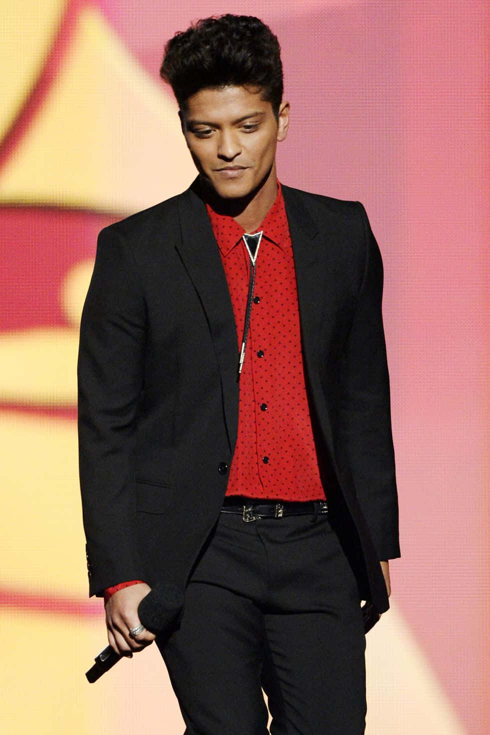 A Man In A Suit And Red Shirt Walking Down The Stage