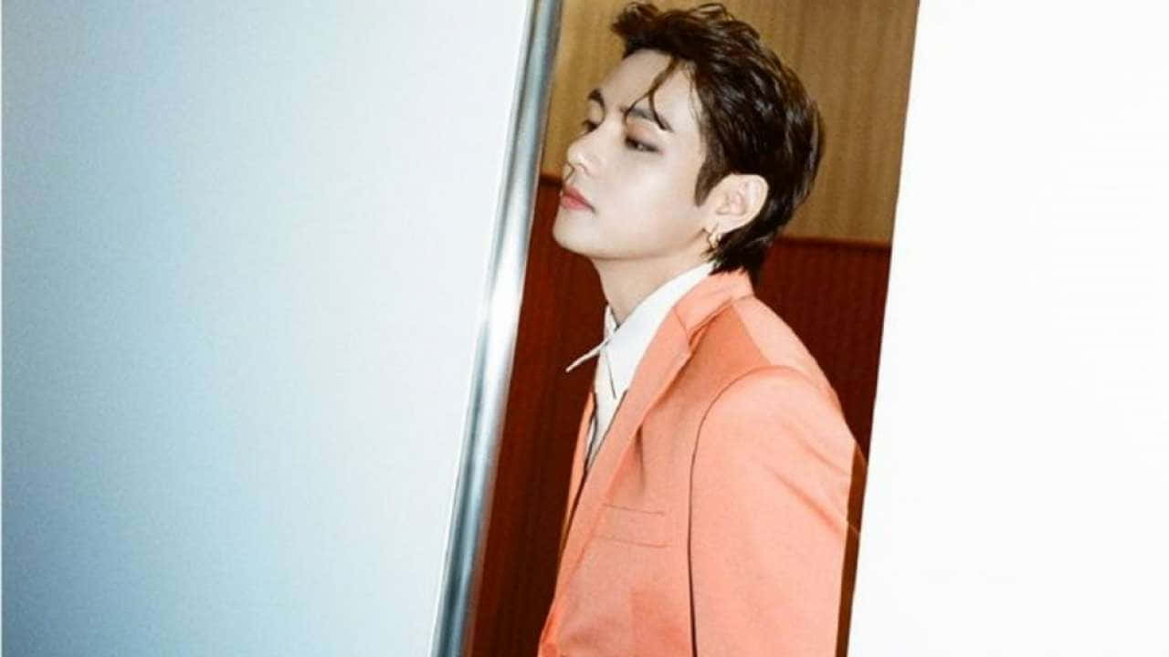 A Man In An Orange Suit Is Leaning Against A Door