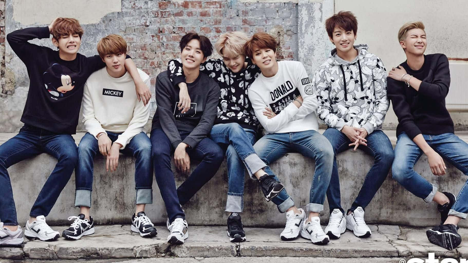 a group of korean boys sitting on a wall