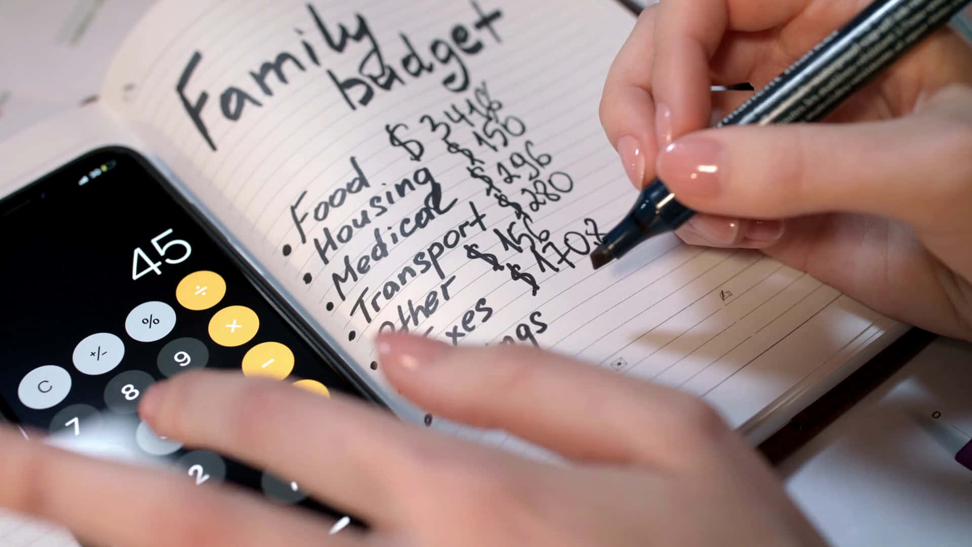 A Person Writing A Family Budget On A Notebook