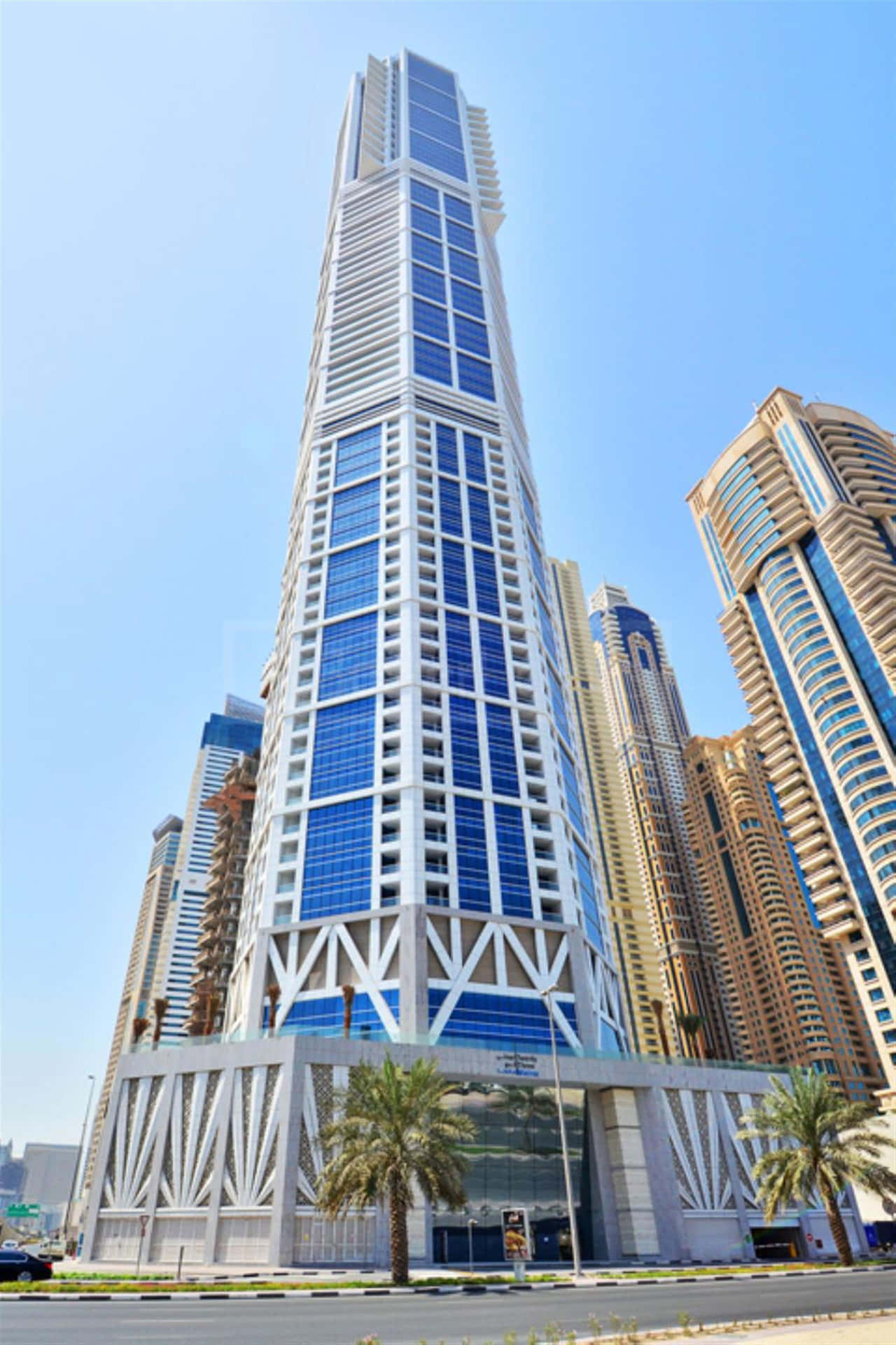 A Tall Building With A Blue Sky And Palm Trees