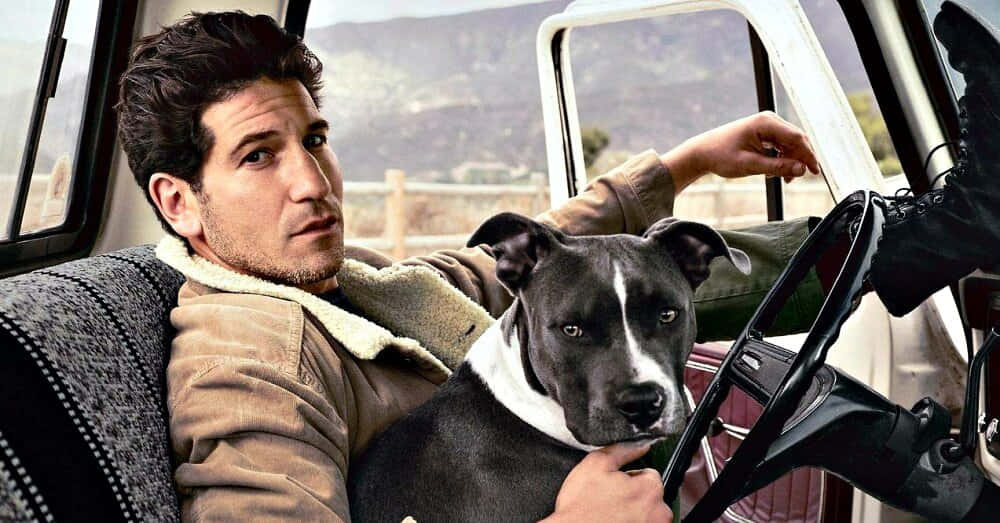 A Man Sitting In A Car With A Dog