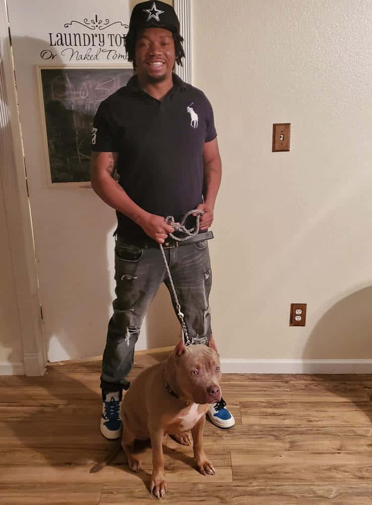 A Man Standing Next To A Dog On A Leash