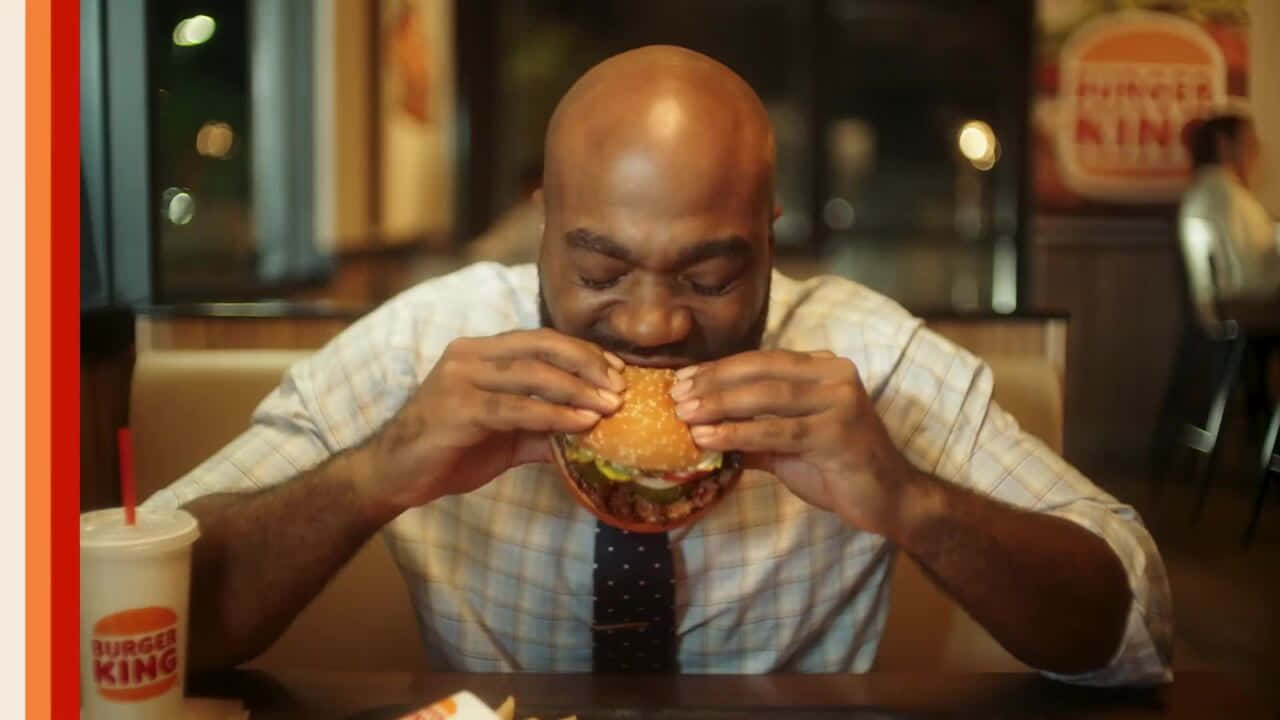 A Man Eating A Burger At A Restaurant
