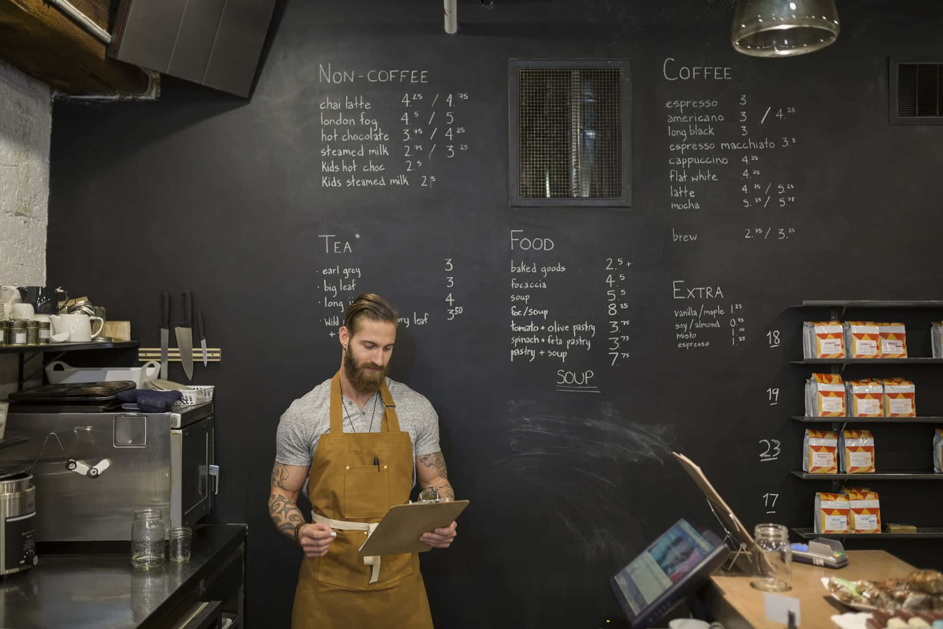 A Man In A Apron Is Standing In Front Of A Chalkboard