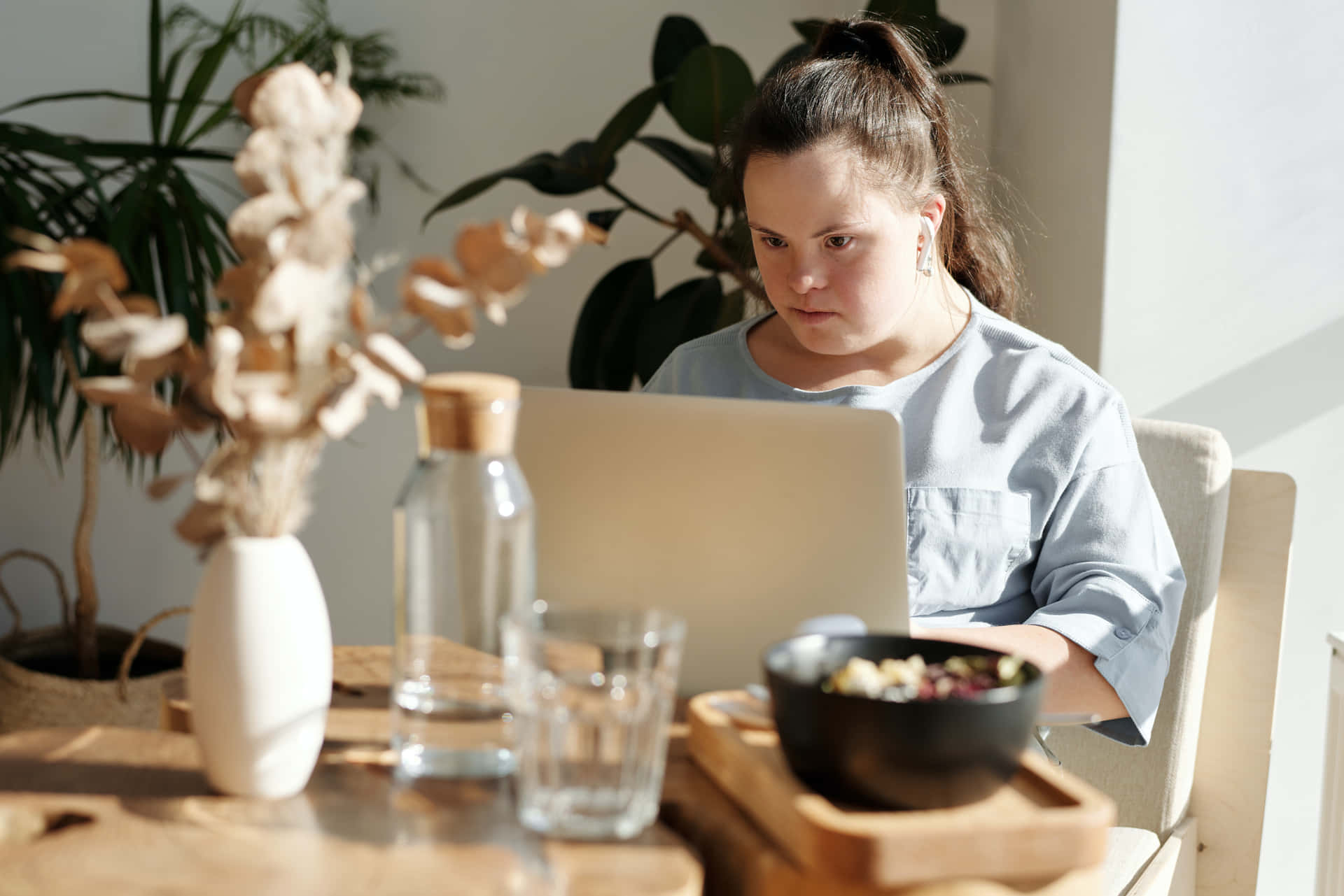 A Woman Sitting At A Table With A Laptop