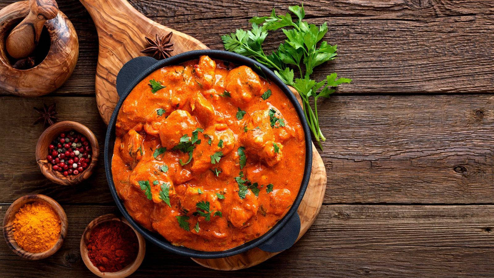 Delicious Butter Chicken Served on a Rustic Wooden Board Wallpaper