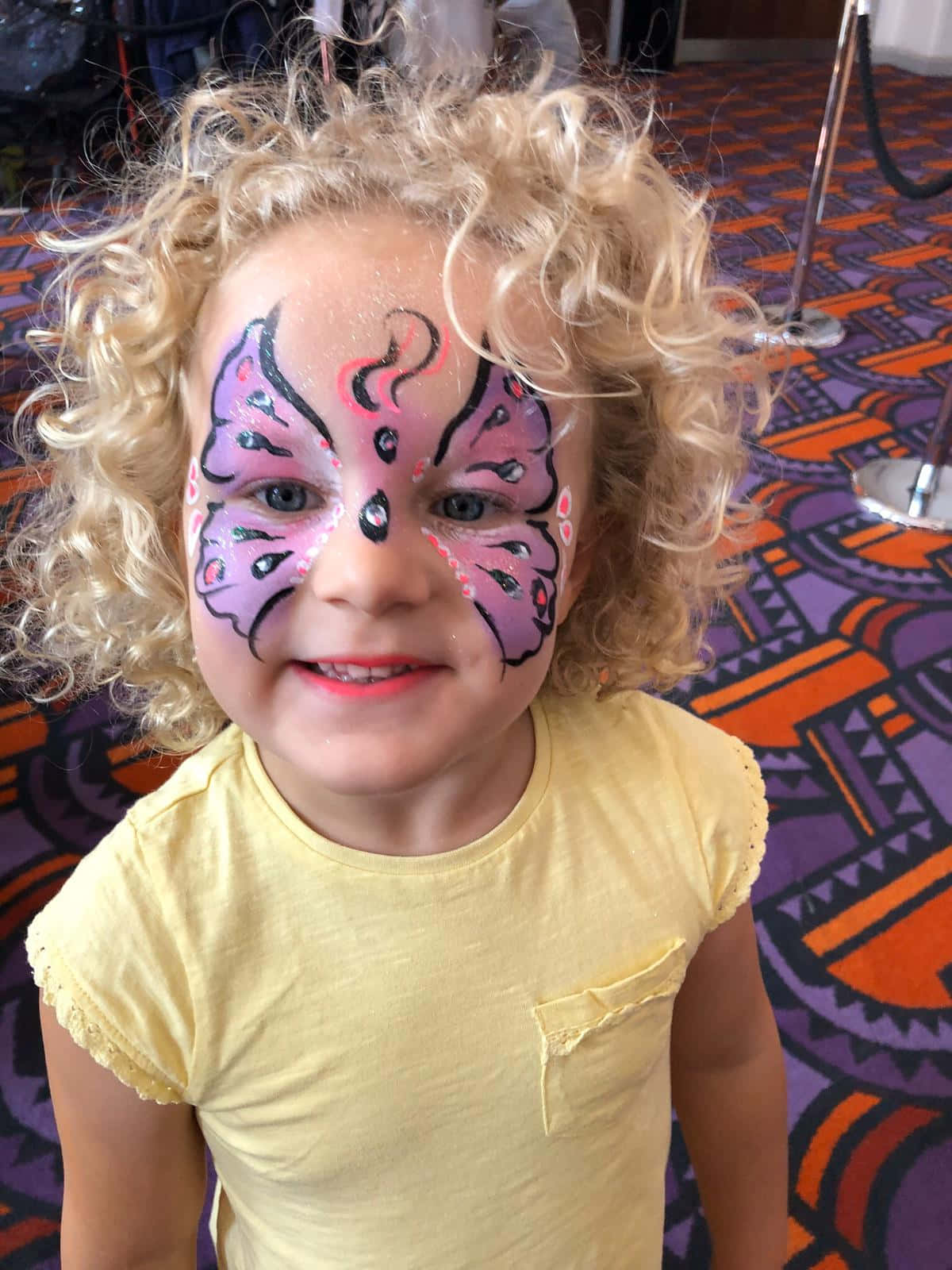 A joyous young girl sporting a beautiful face painting of a butterfly. Wallpaper