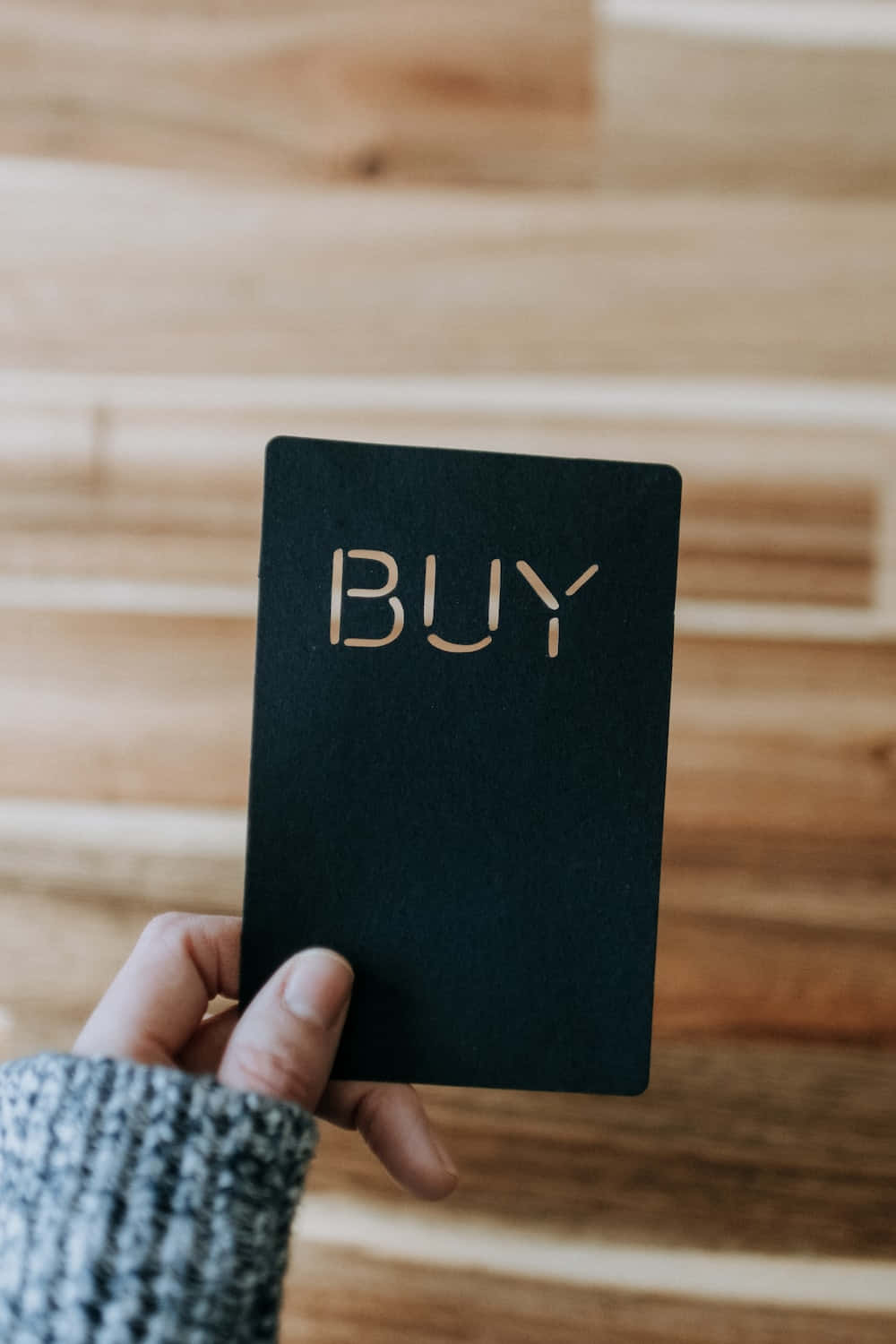 A Person Holding A Black Card With The Word Buy On It