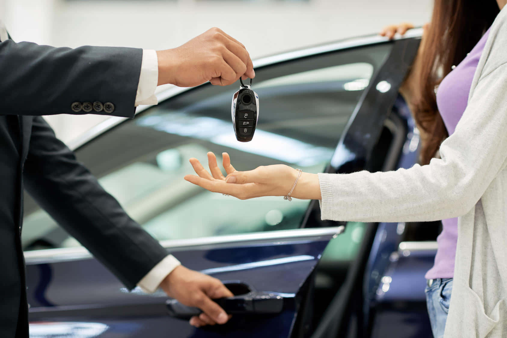 A Man And Woman Handing A Car Key To Each Other