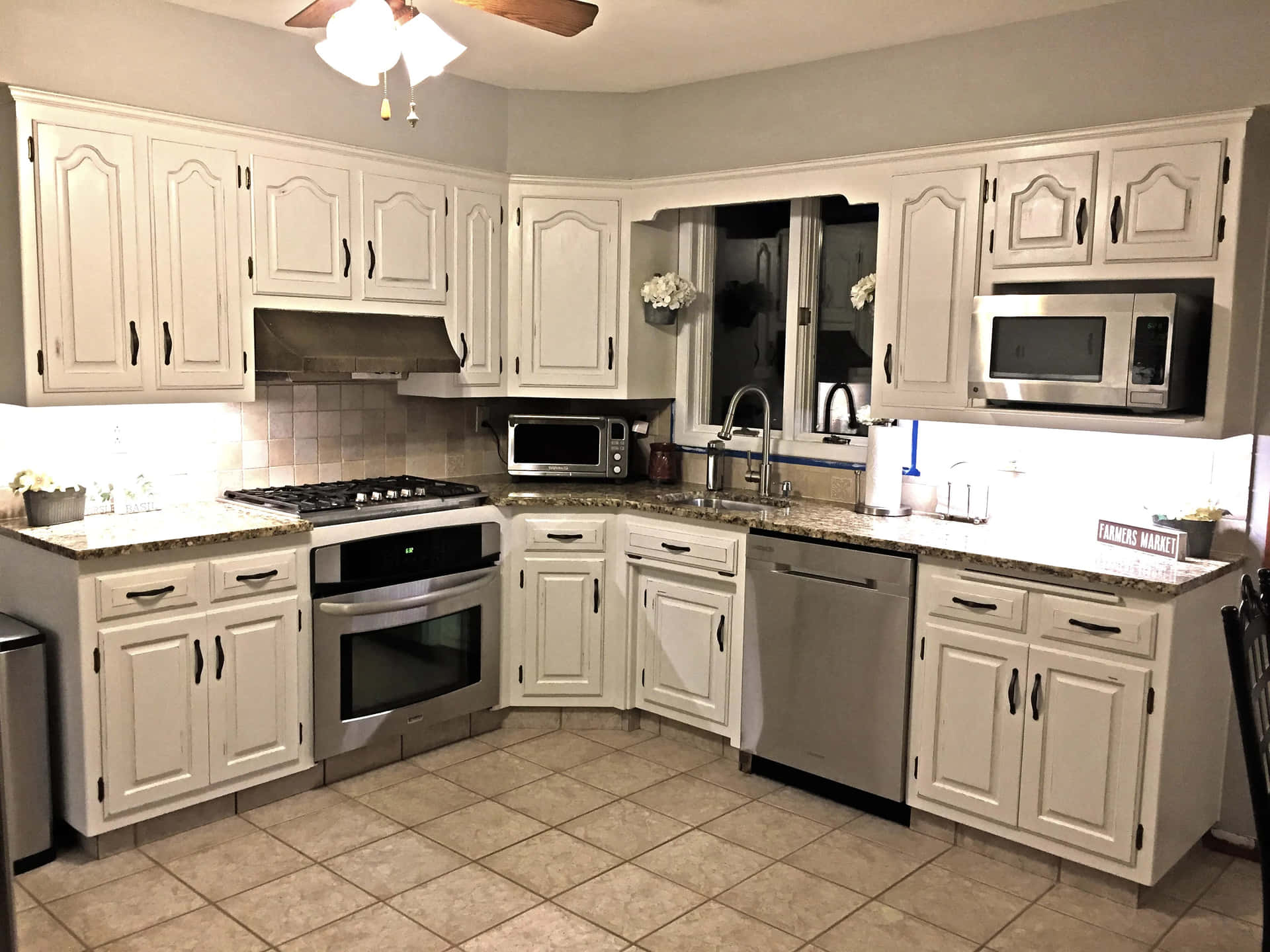 A Kitchen With White Cabinets And A Ceiling Fan