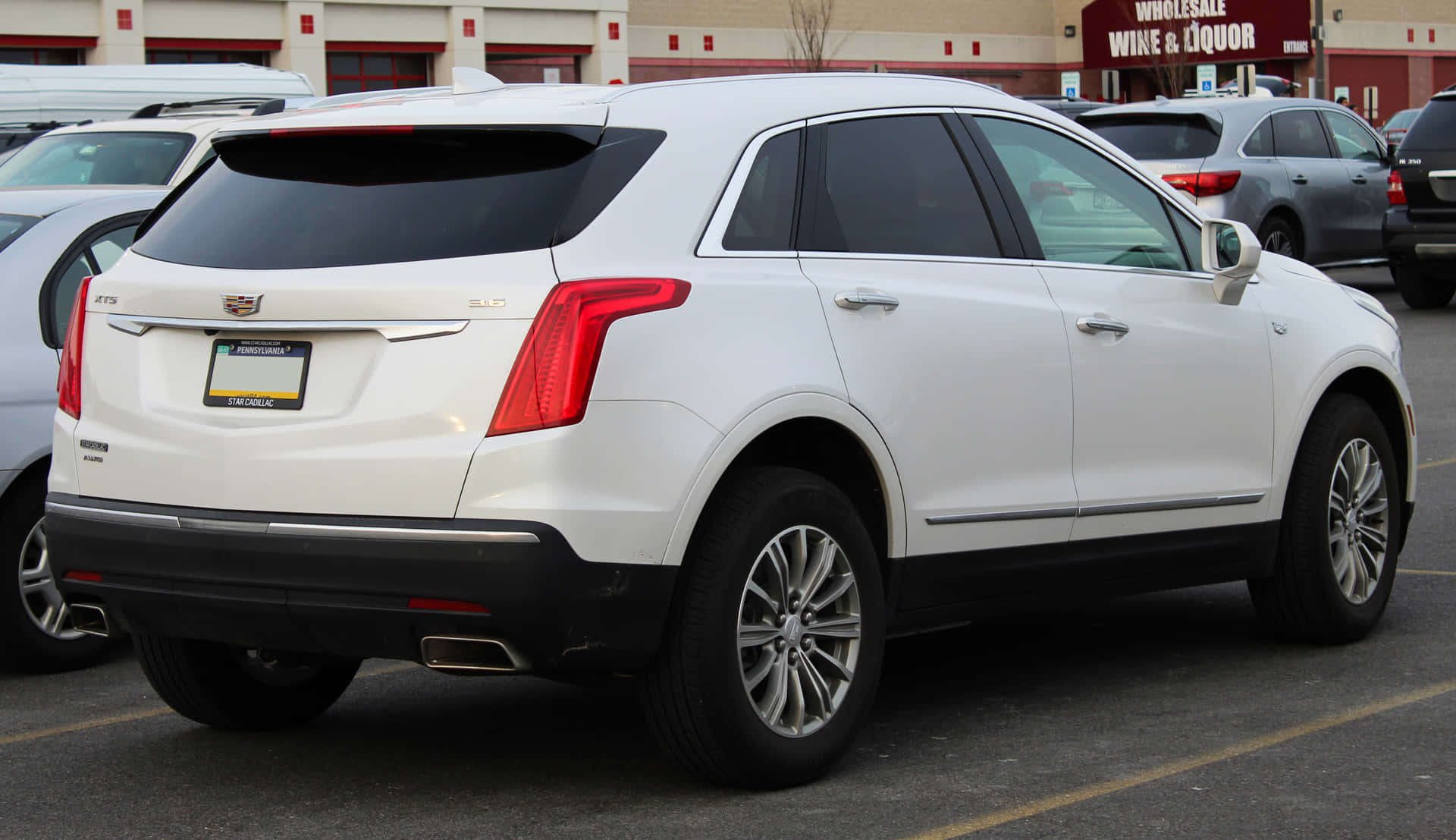 A sleek black Cadillac XT5 parked on a modern city street Wallpaper