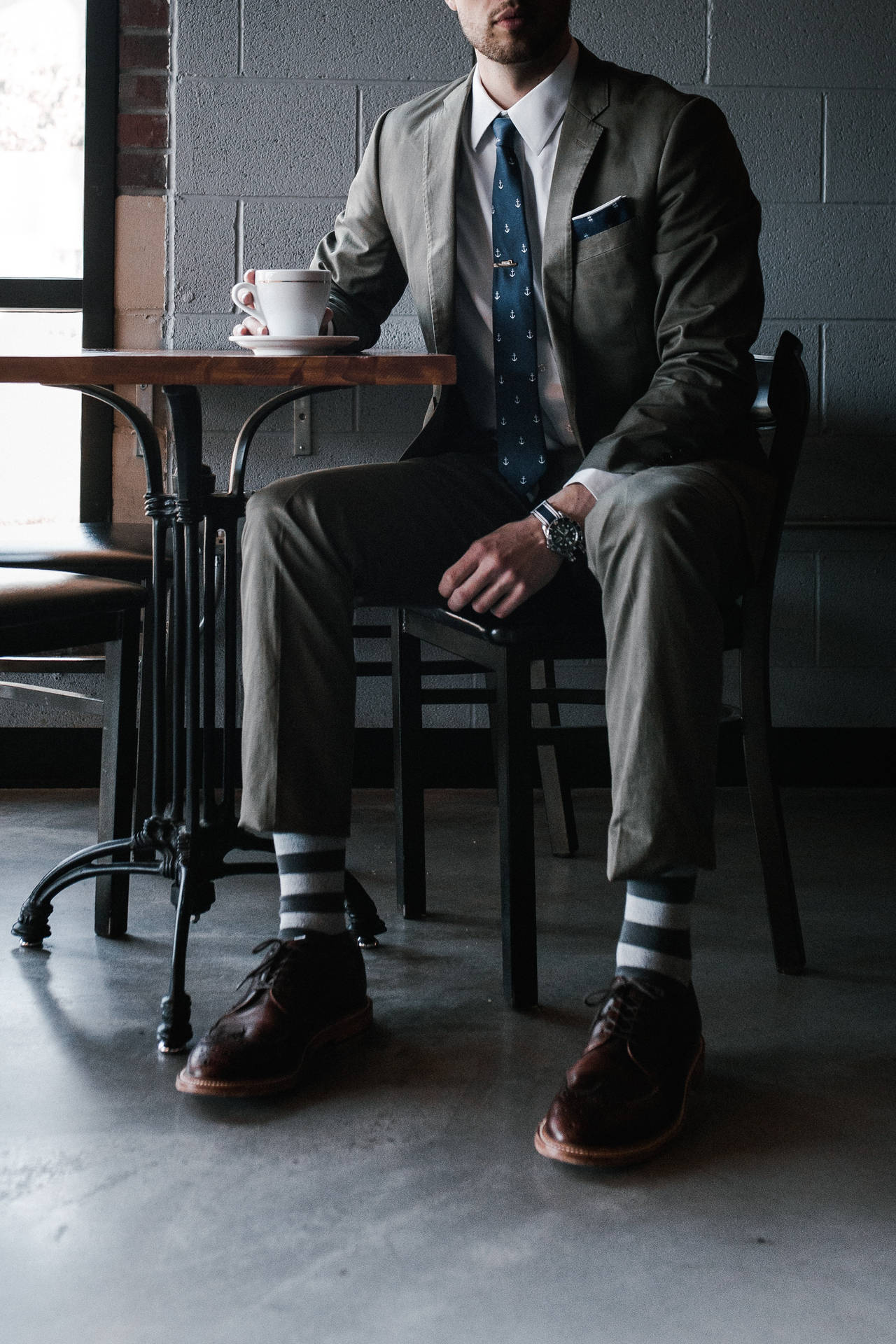 Trendy Man in Stylish Attire Posing at a Café Wallpaper